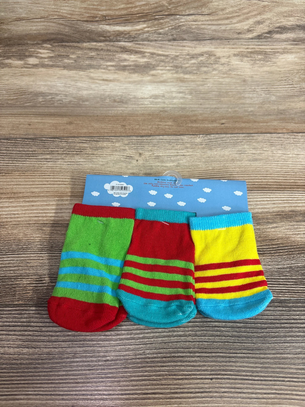 Front view of NEW 3pk Monster Face Baby Socks sz 12-24m showcasing colorful striped designs on wood background