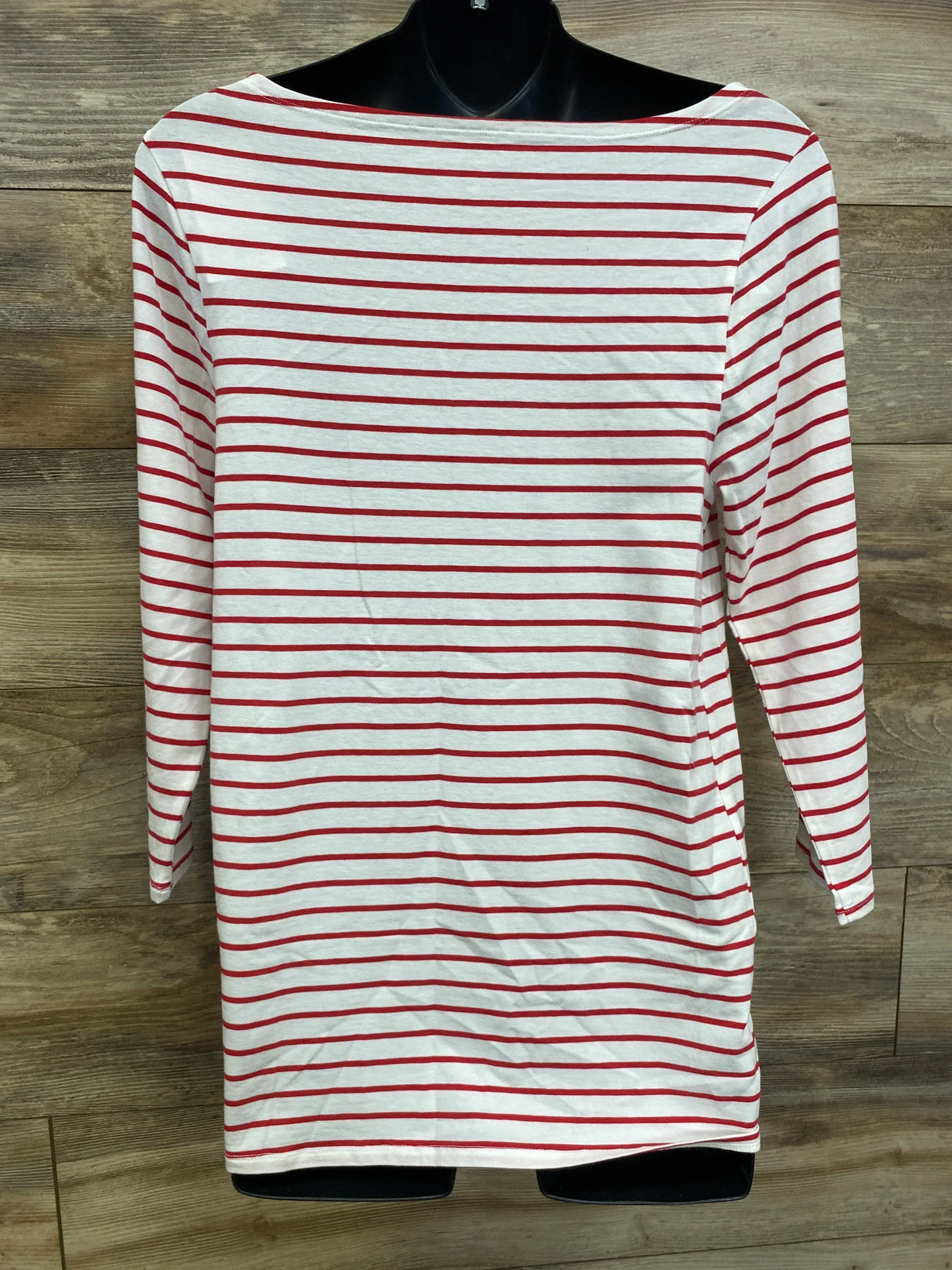 White long sleeve shirt with red horizontal stripes, displayed on mannequin, wood background