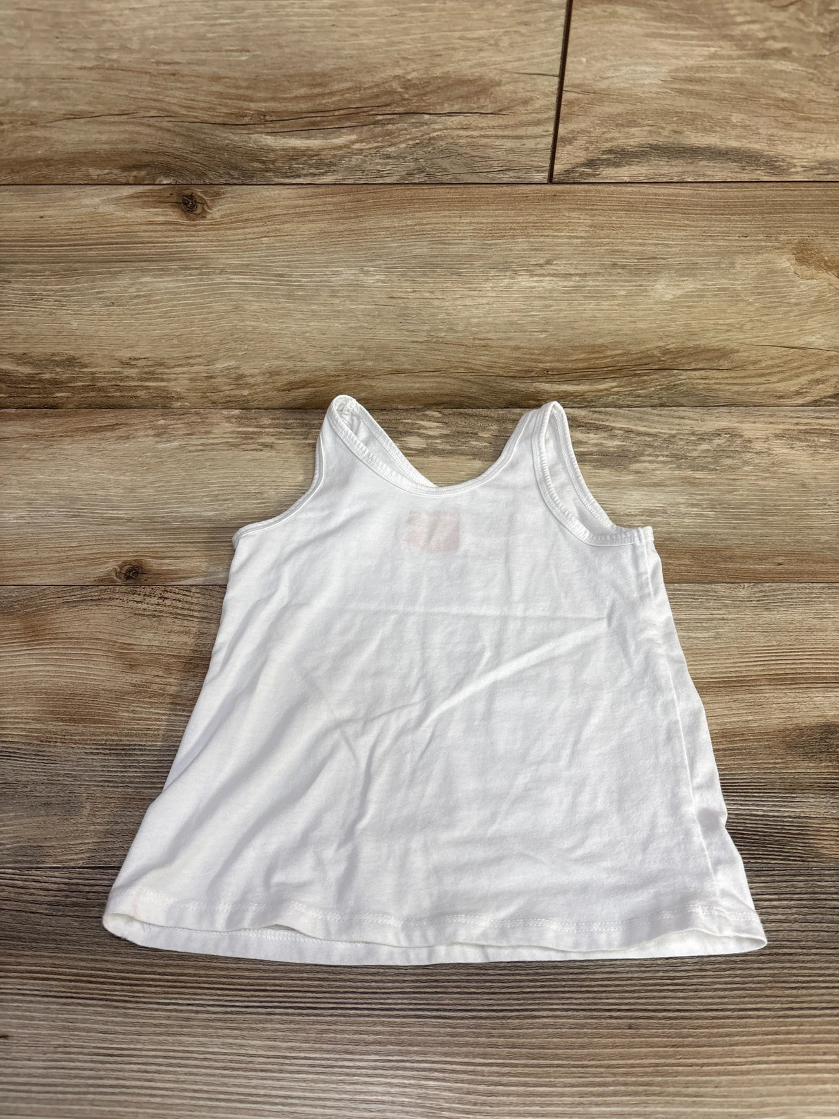 Flat-lay of white Cat & Jack toddler tank top, size 4/5T, with scoop neckline and sleeveless cut on wood floor