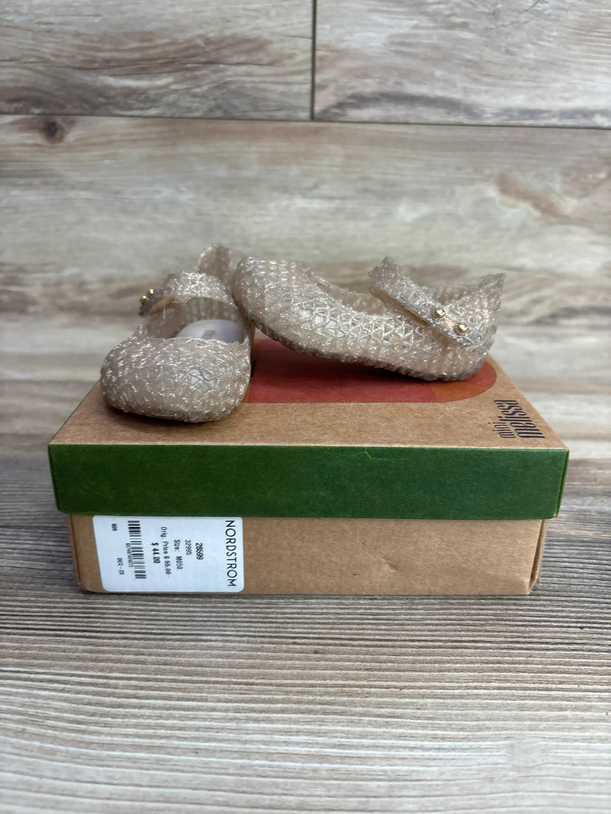 Glittery toddler Mary Jane shoes with straps on a Nordstrom shoe box, wood background