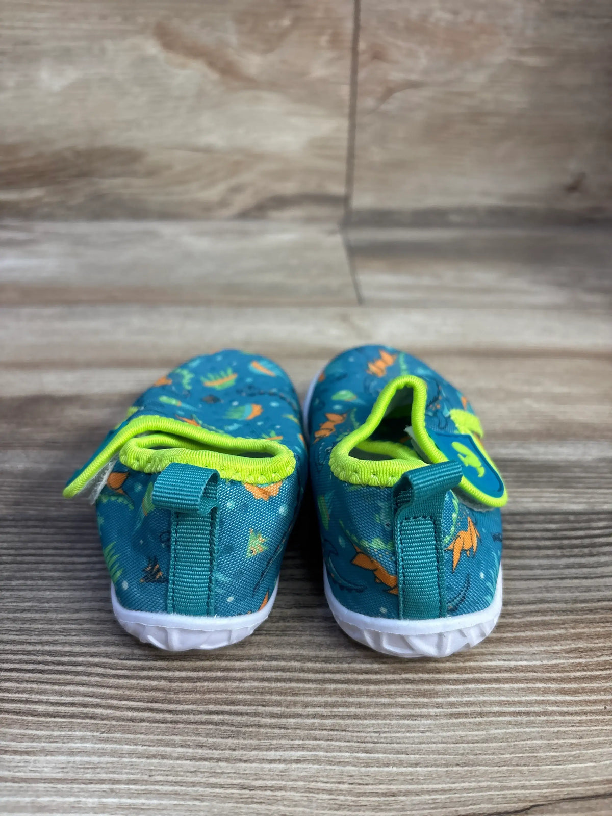 Front view of FEETCITY wide barefoot water shoes in teal with lime green trim, pull tabs, and white textured soles on woodgrain