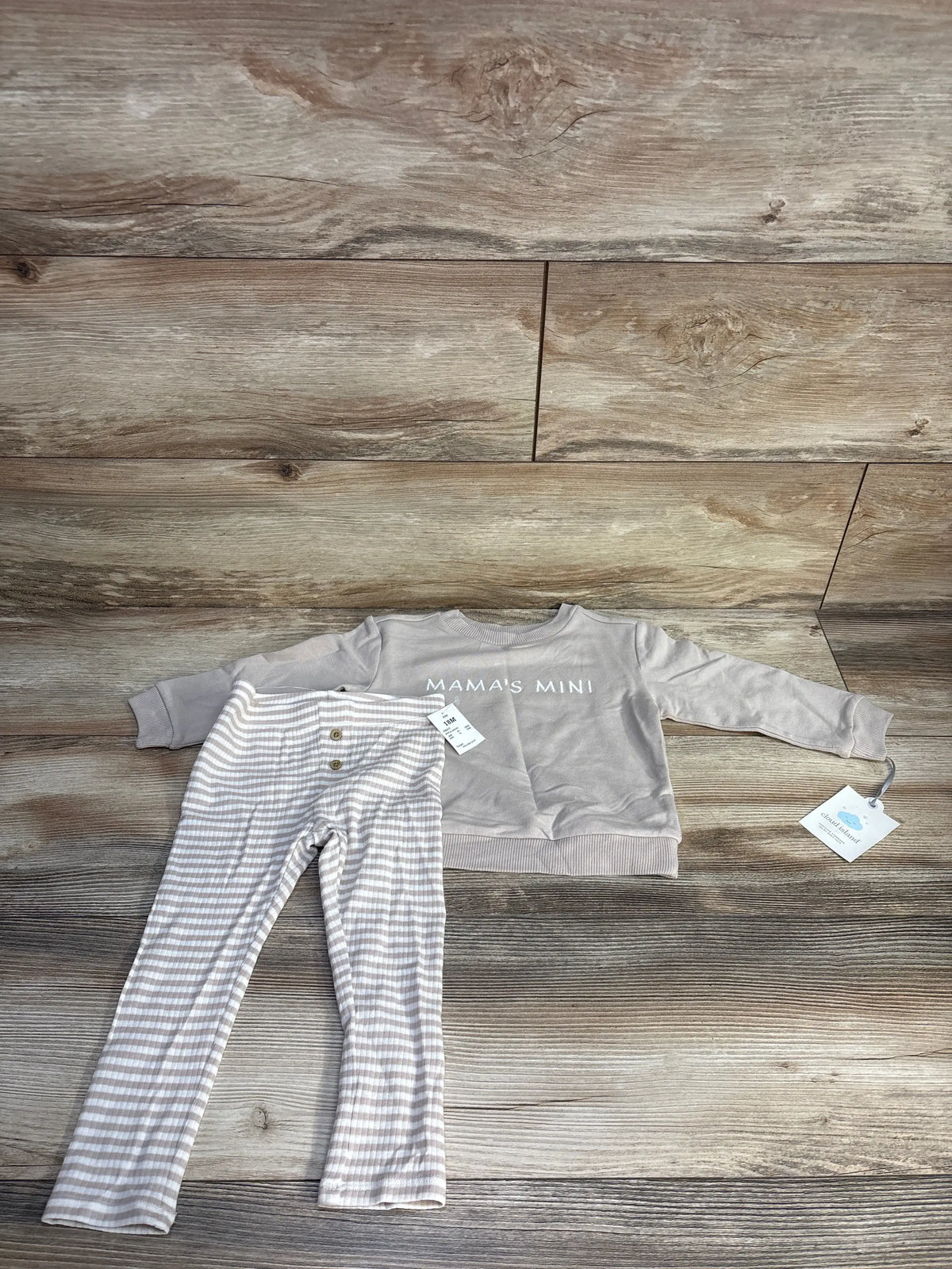 Overhead view of beige Cloud Island two-piece sweatshirt and striped pants set showcasing Mama’s Mini text on a wood floor