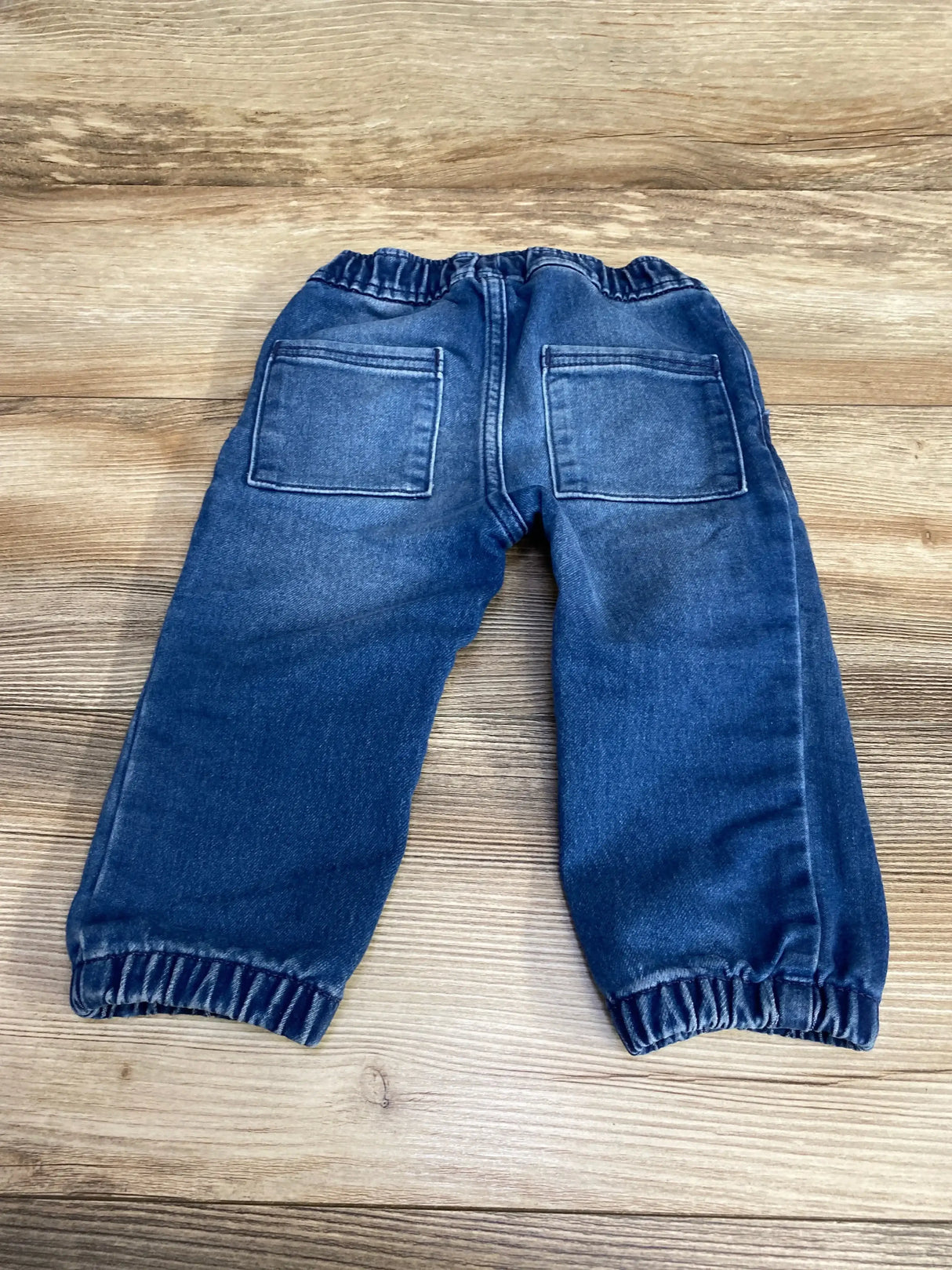 Front view of Baby Gap blue jogger jeans showing elastic waistband and cuffed ankles on white background