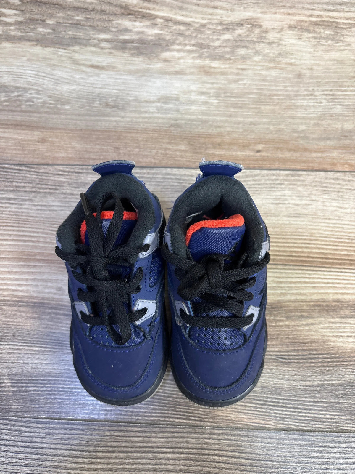 Front view of Air Jordan 4 Retro TD toddler sneakers showcasing Loyal Blue colorway and black laces on a wood-grain surface