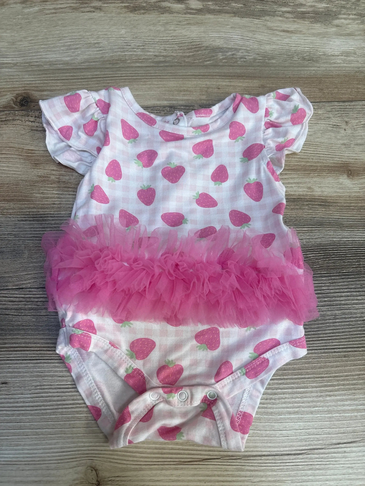 Pink strawberry print baby girl bodysuit with ruffled tutu on wood background