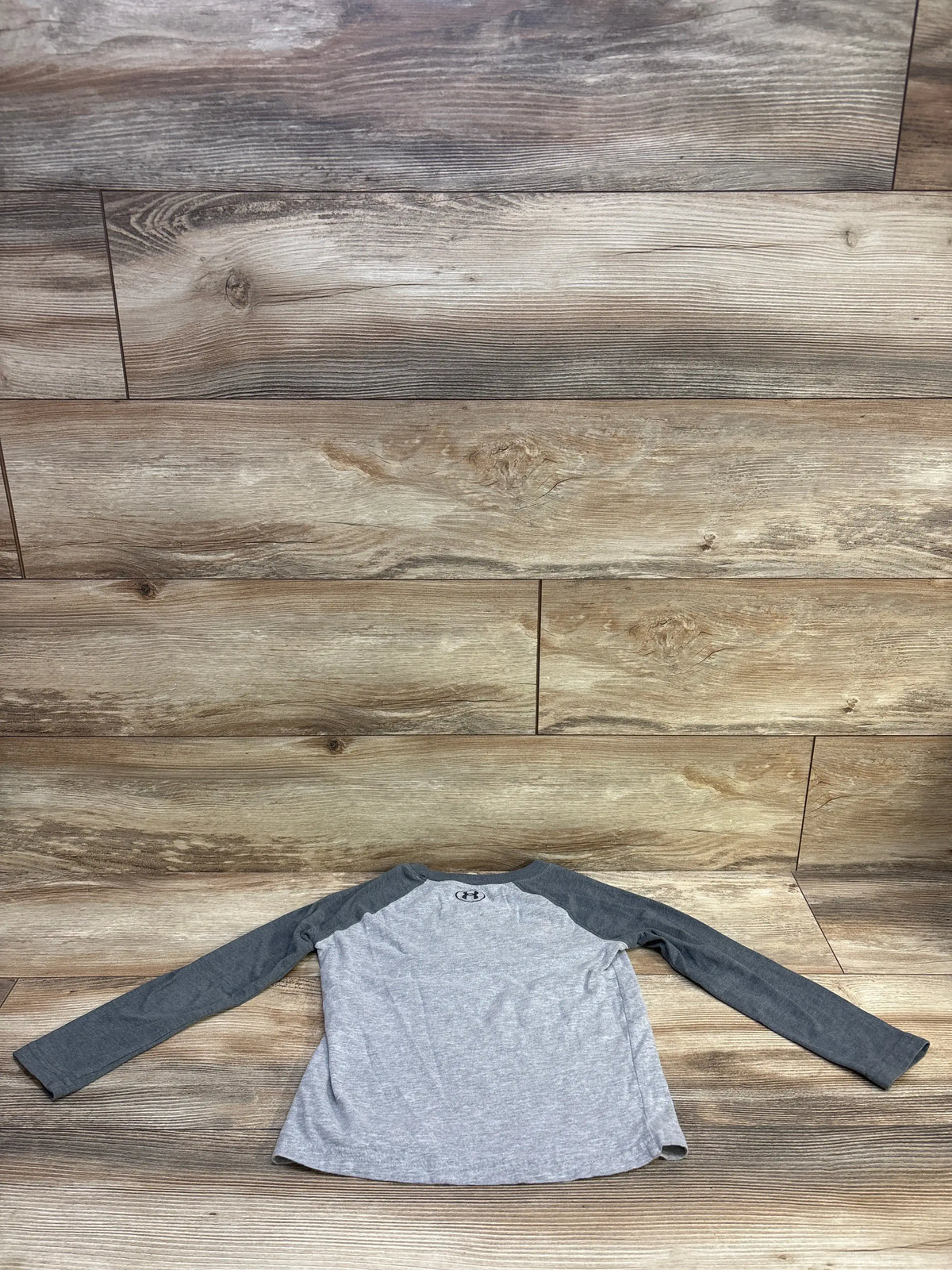 Grey and charcoal long sleeve Under Armour logo shirt for kids size 5T on wood background