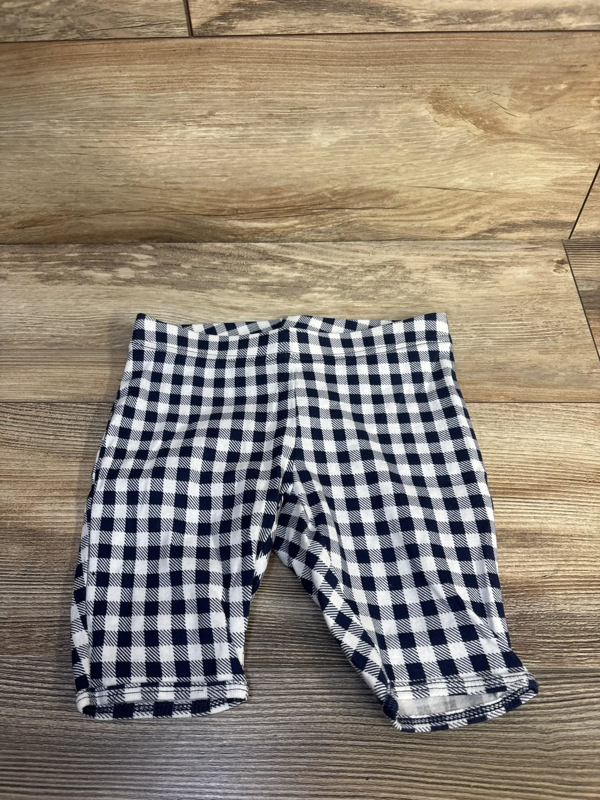 Flat lay of Old Navy toddler bike shorts size 5T showcasing navy and white gingham pattern and elastic waist on wood floor