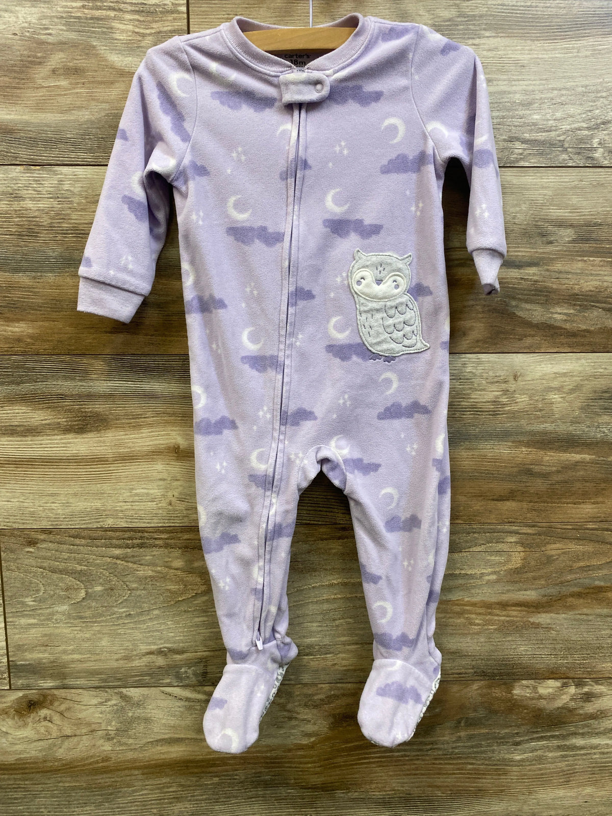 Front view of Carter’s purple blanket sleeper showcasing full-length zipper, footed legs, and owl detail with a wood background