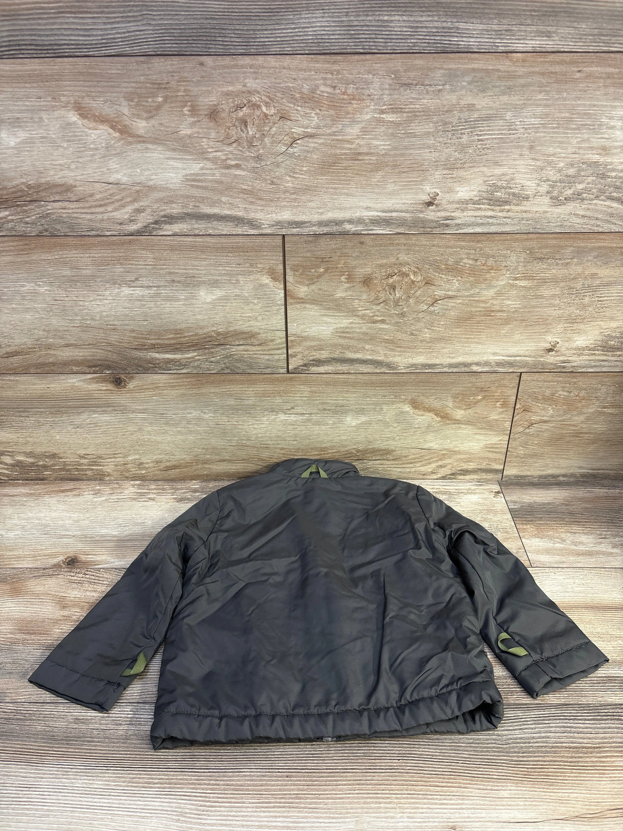 Back view of Cat & Jack lined green windbreaker jacket, size 3T, showing elastic hem and sleeve tab on wood floor