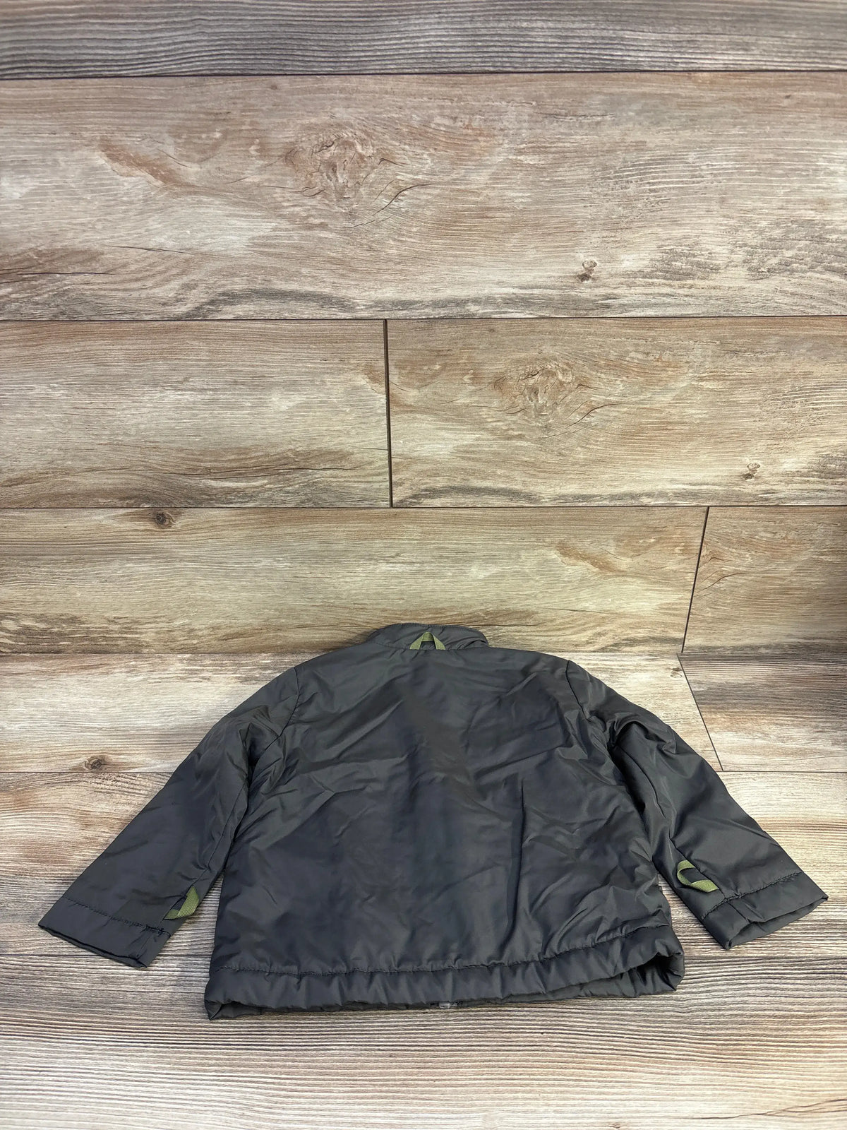 Back view of Cat & Jack lined green windbreaker jacket, size 3T, showing elastic hem and sleeve tab on wood floor