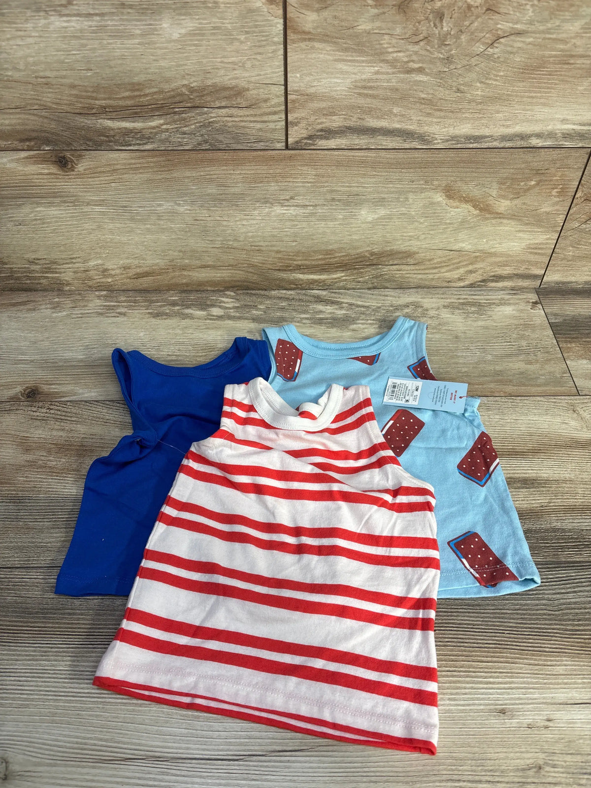 Set of three baby tank tops: one solid blue, one red and white striped, and one light blue with ice cream prints.