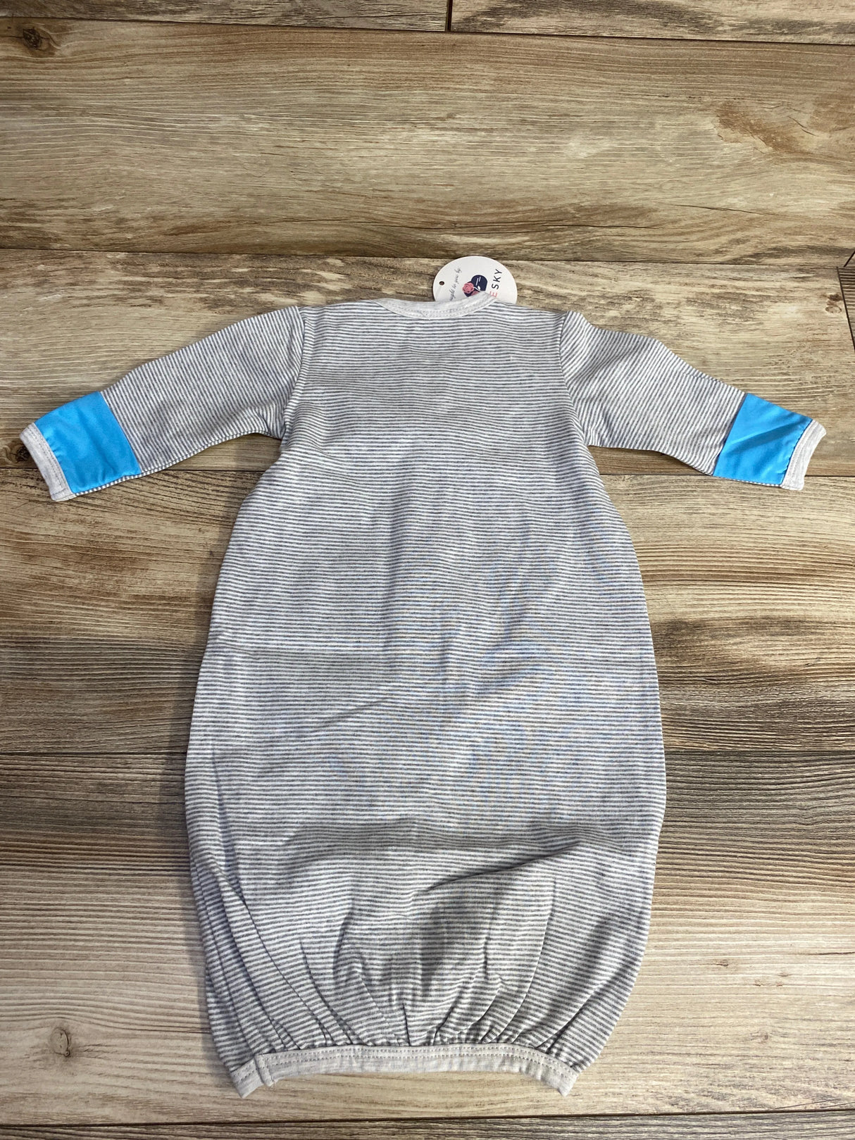Gray striped baby gown with long sleeves and blue elbow patches on wooden surface