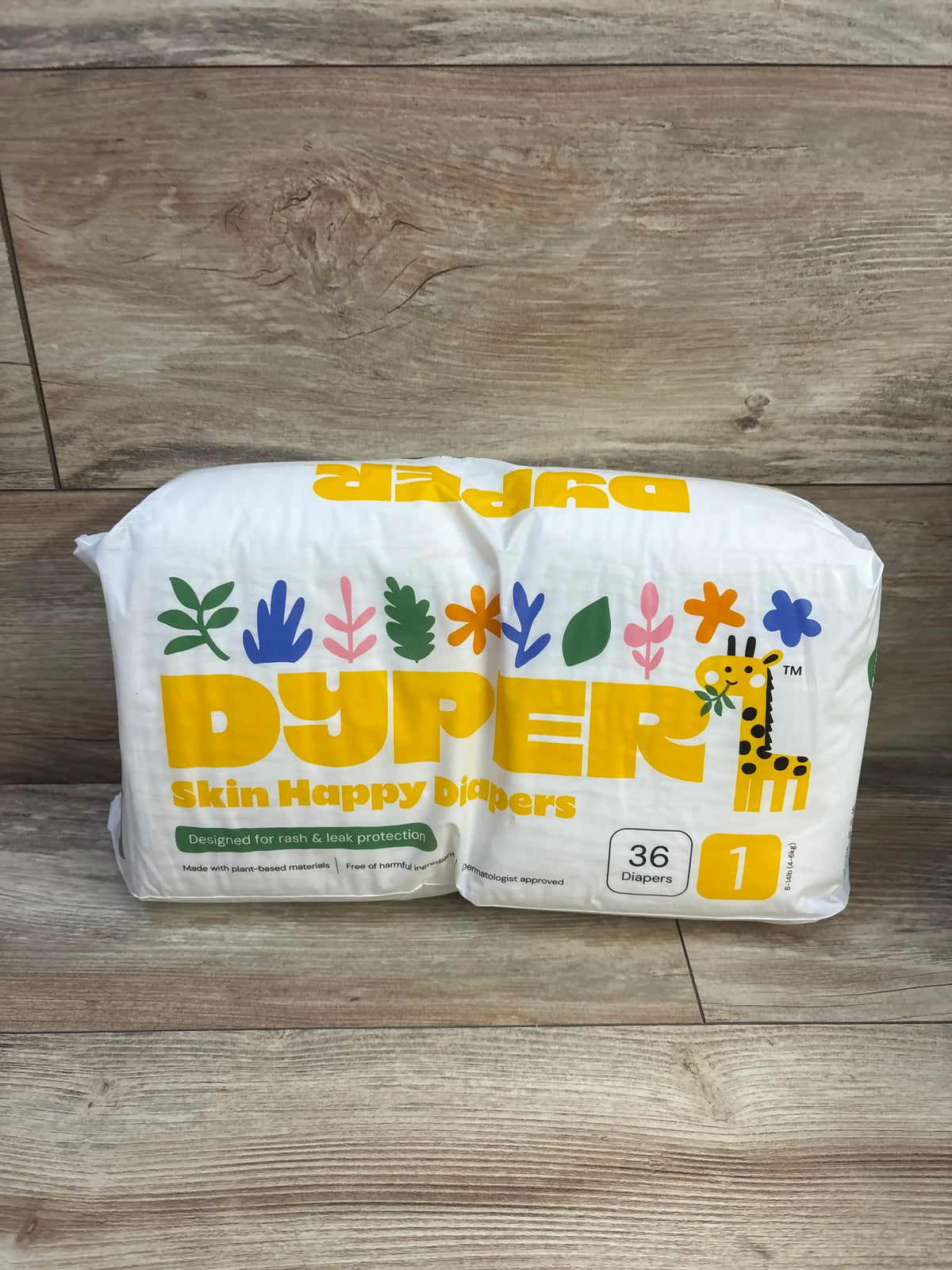 Front view of Dyper Skin Happy diapers pack showcasing yellow DYPER logo, size 1 36-count label and giraffe illustration on wood floor background