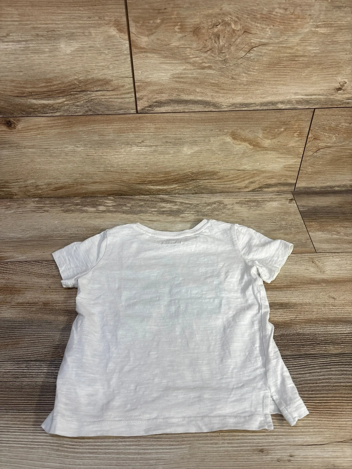 Back view of white Cherubino toddler t-shirt showcasing short sleeves, slub texture and side hem slit on wood floor