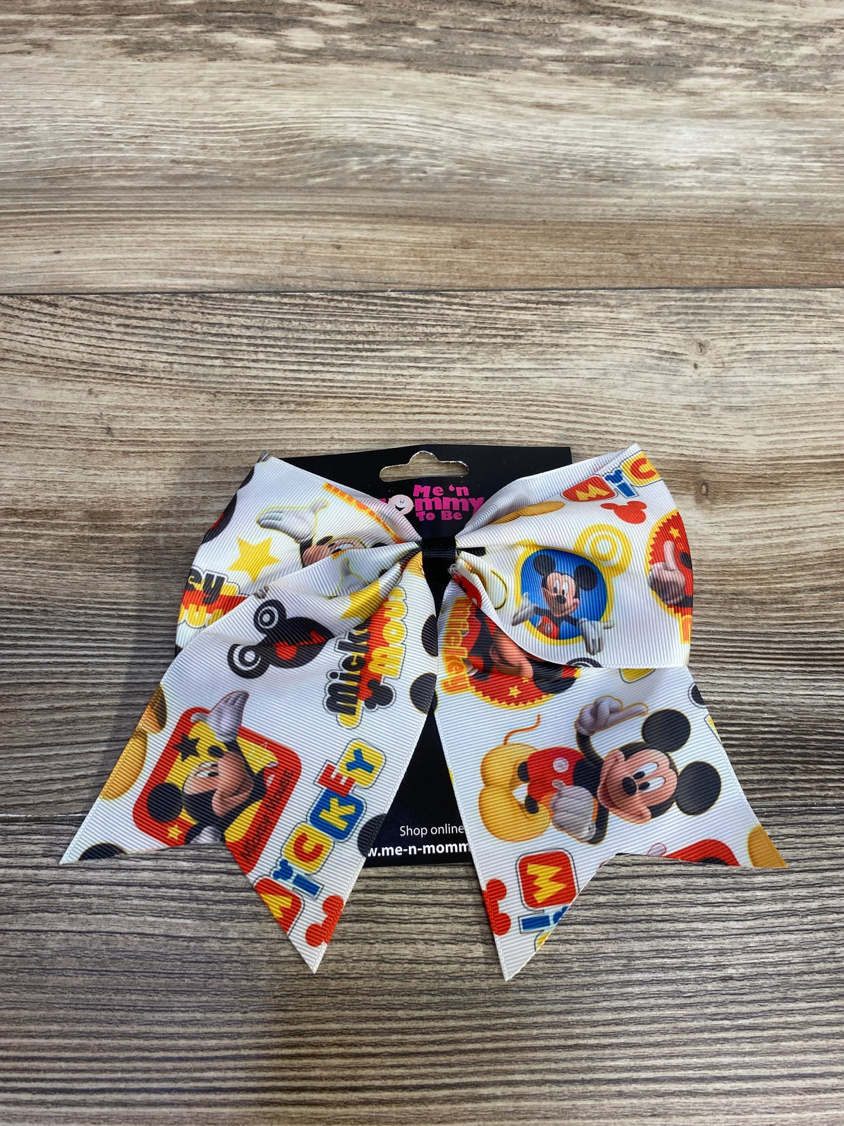White Mickey Mouse themed bow with colorful cartoon prints on a wooden surface