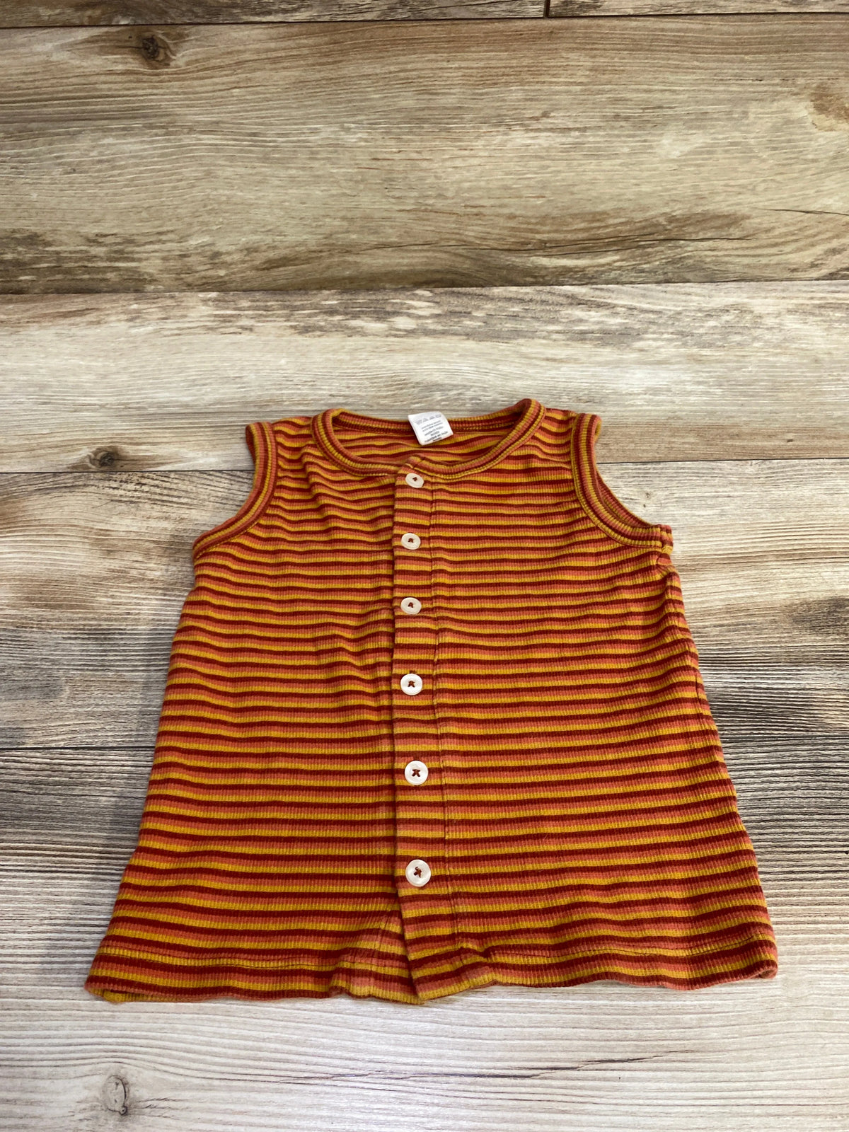 Top-down view of Kate Quinn orange striped button-up tank top in size 3T with front buttons on wood-grain background