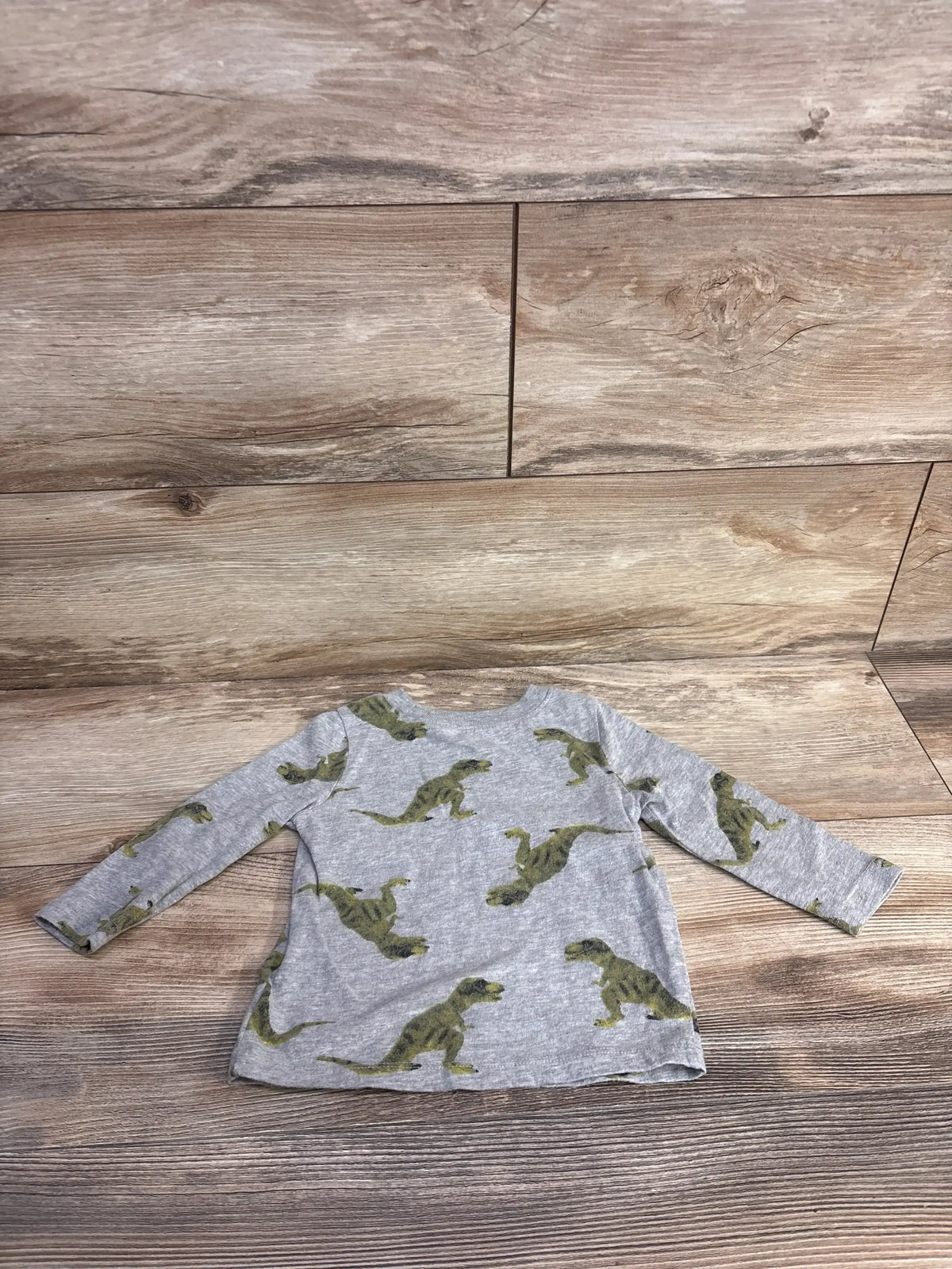 Front flat lay of Old Navy grey long-sleeve toddler shirt showcasing green dinosaur print with wood plank background