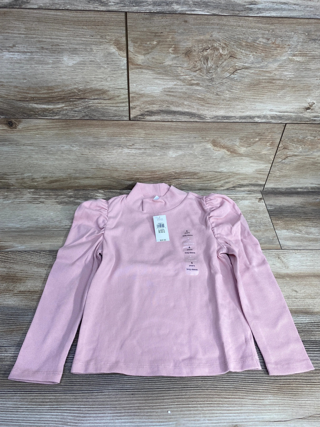 Light pink long sleeve toddler shirt with puff shoulders on wood background