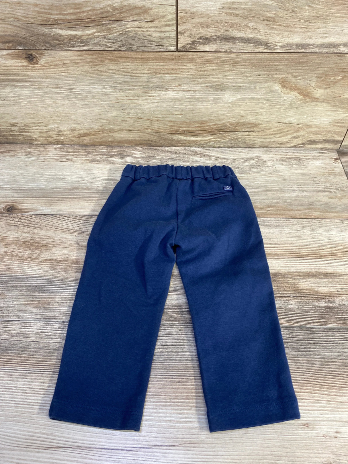 Back view of navy toddler dress pants size 12 month showing elastic waistband and faux back pocket on wood floor background