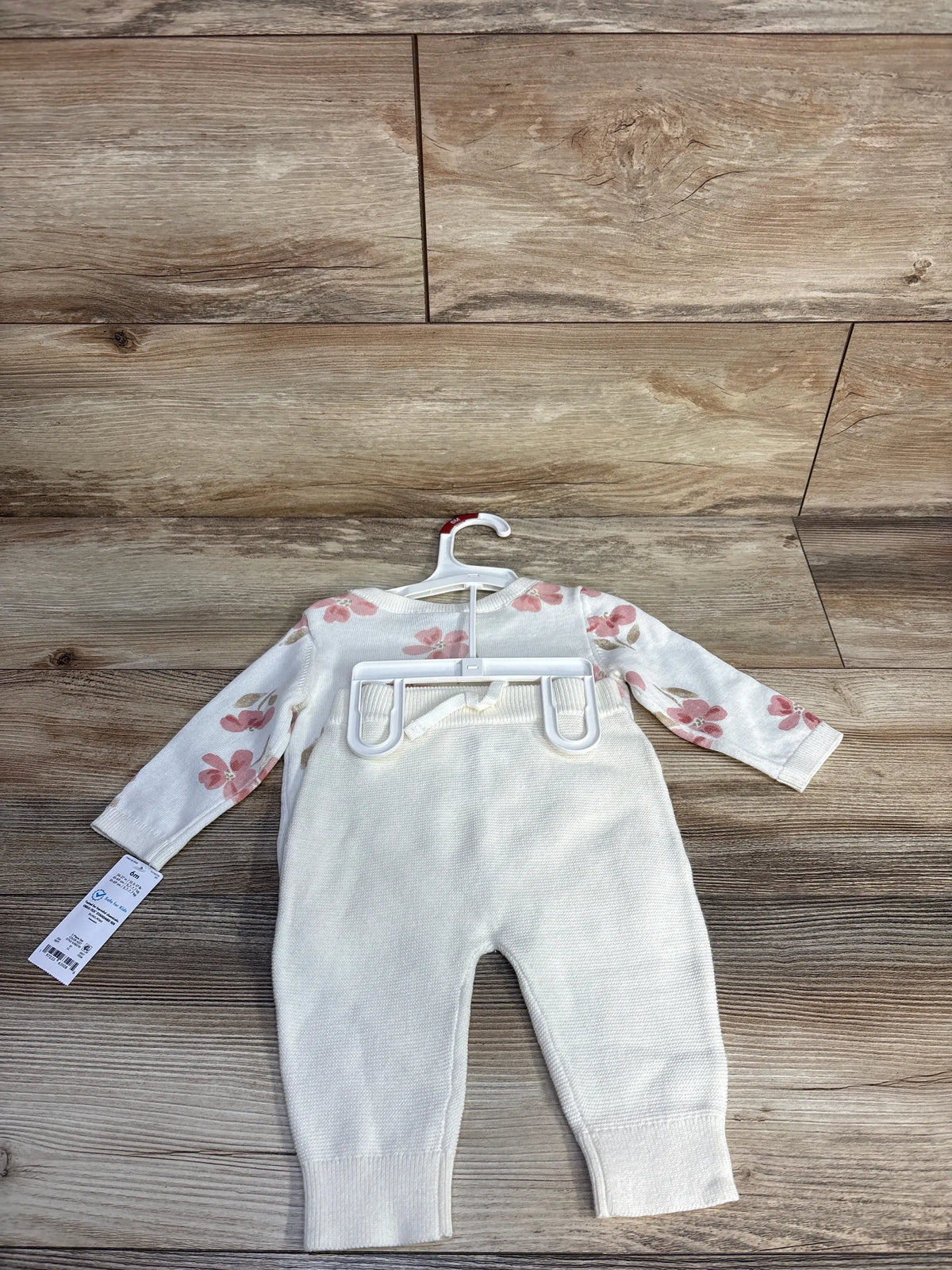 Front view of Just One You ivory knit sweatshirt and pants set showcasing floral sleeves on a wood background