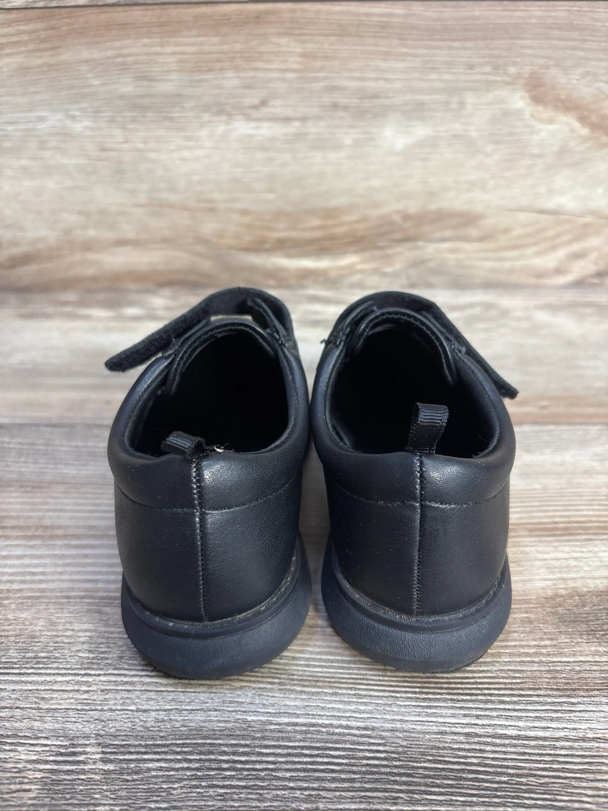 Rear view of Wonder Nation black Oxford dress shoes in size 11C showing stitched heels on a wood-grain surface