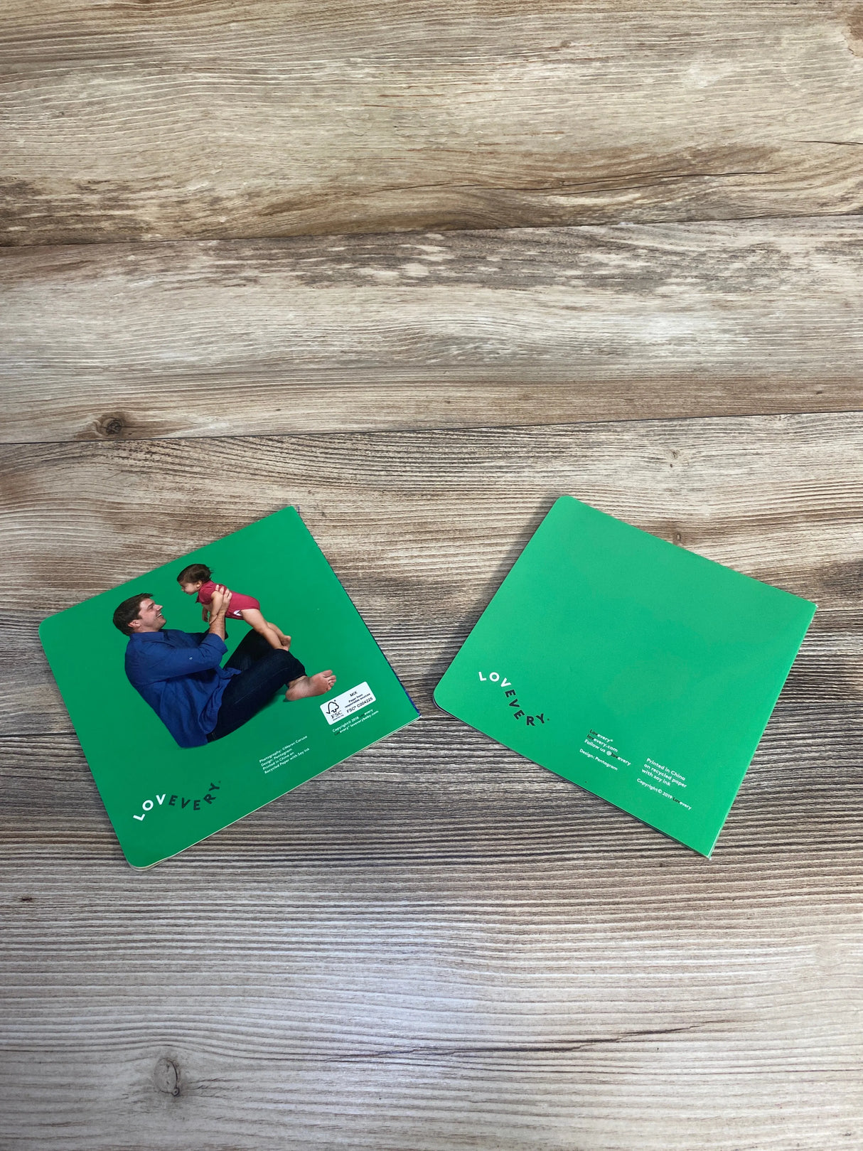 Green Lovevery educational cards on wooden surface, one showing father playing with baby