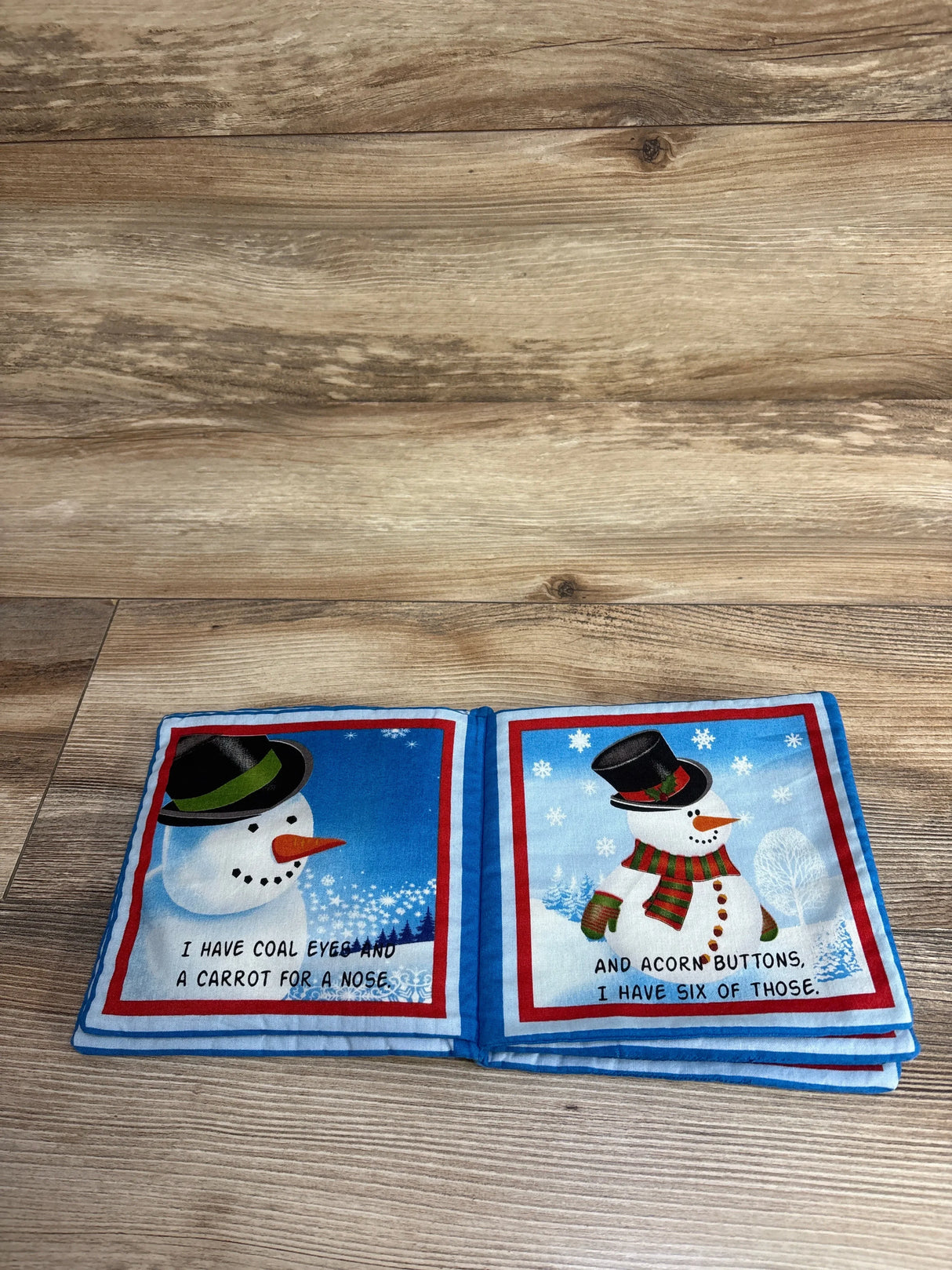Soft fabric children’s book with snowman illustrations, carrot nose, coal eyes, winter scene