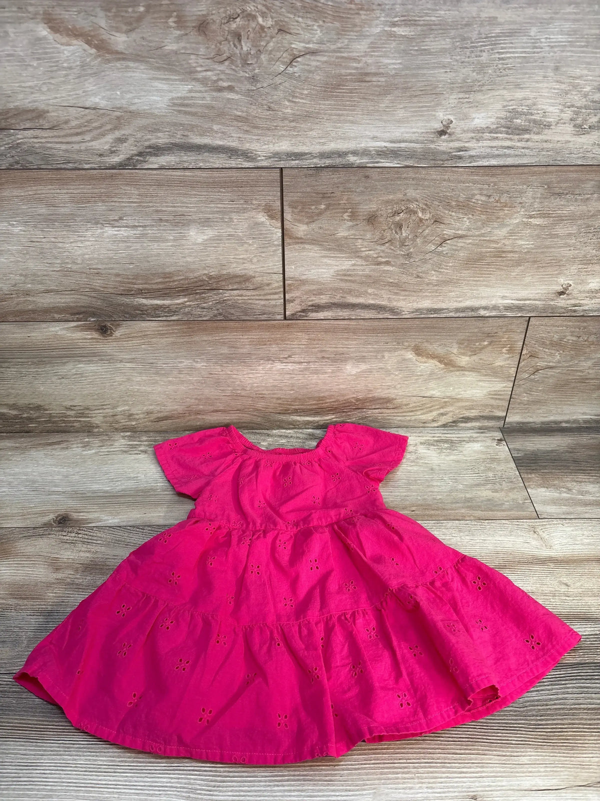 Bright pink eyelet short sleeve toddler dress on wood background