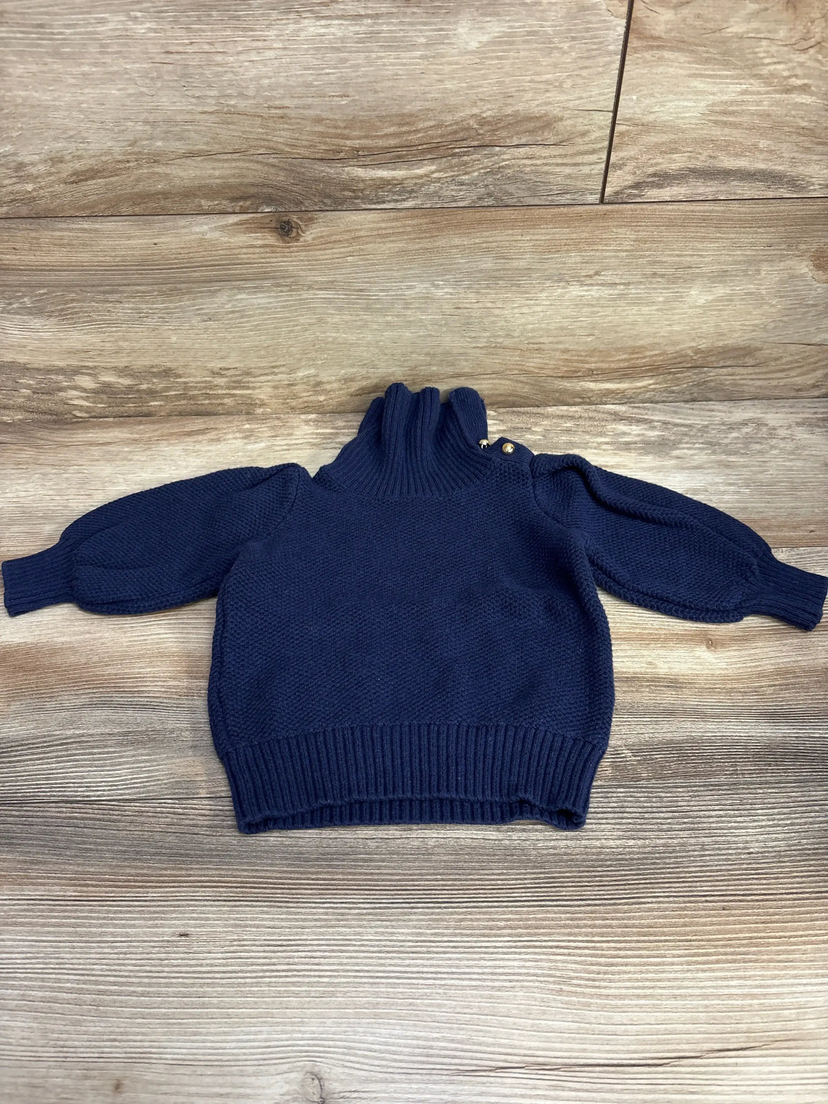 Flat lay of Janie and Jack navy toddler sweater 2T showing ribbed high neck, gold shoulder buttons, puffed sleeves on wood