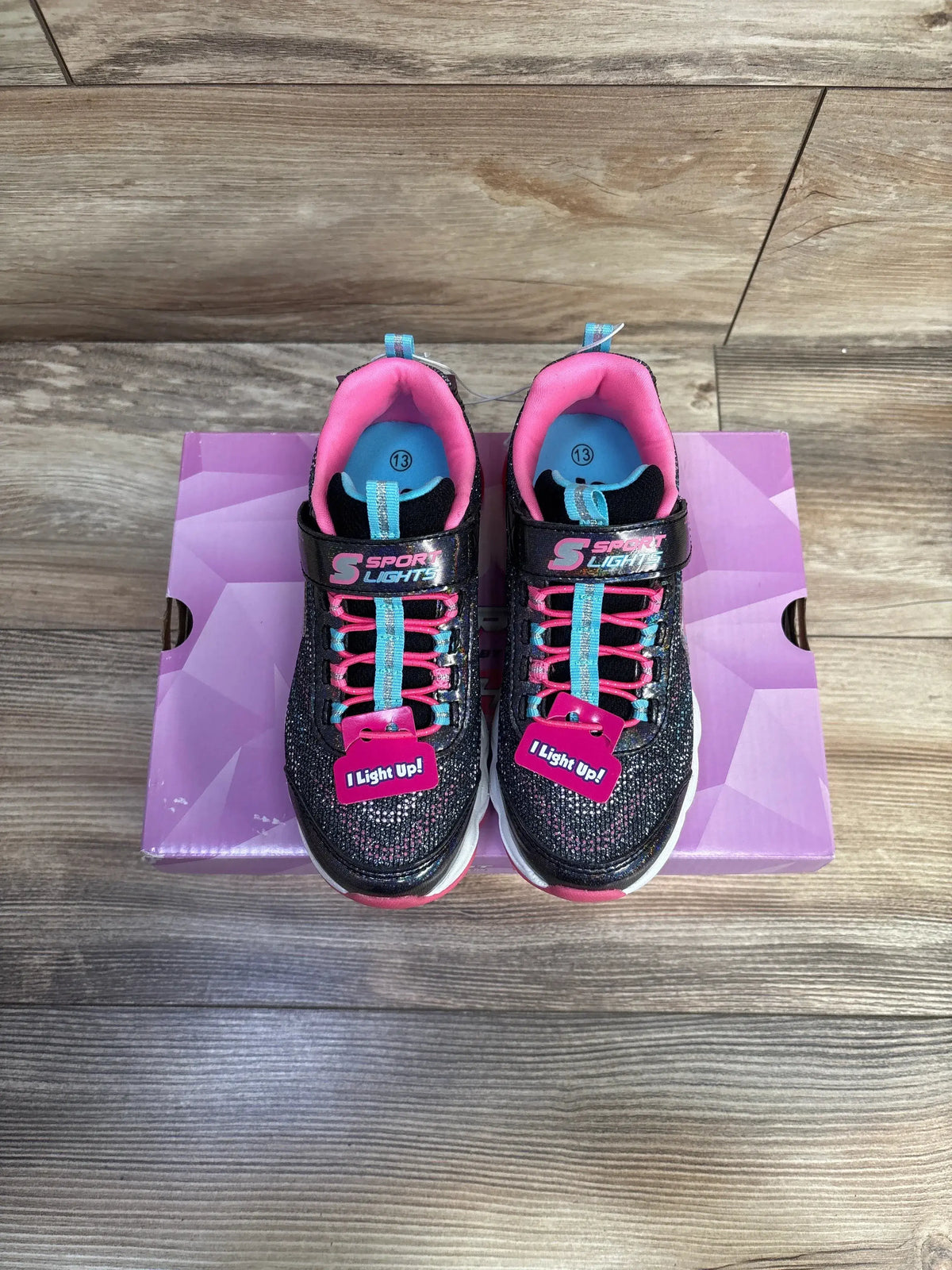 Top view of NEW Skechers S Sport Katalyna Sneakers sz 13c in black glitter with pink and teal accents on purple box on wood floor