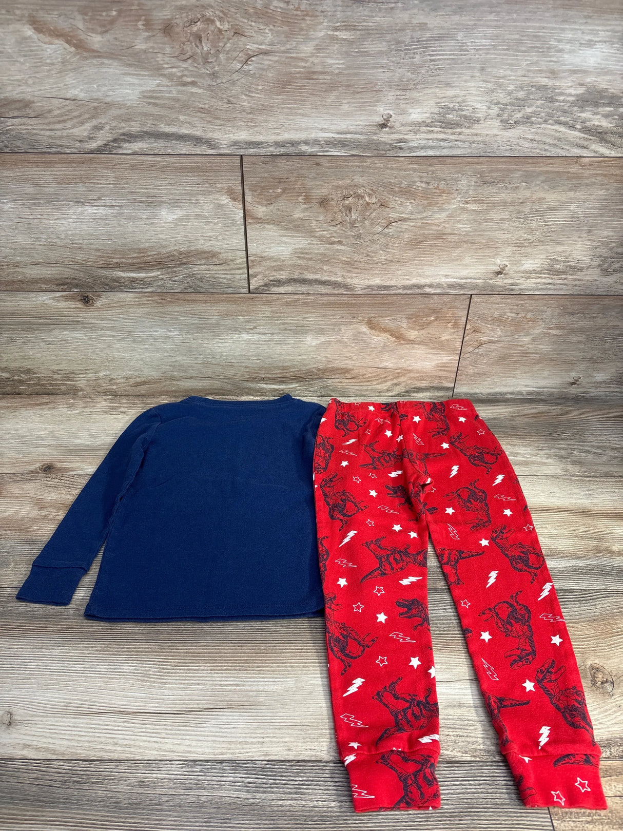 Kids long sleeve navy shirt with red dinosaur pajama pants on wood background