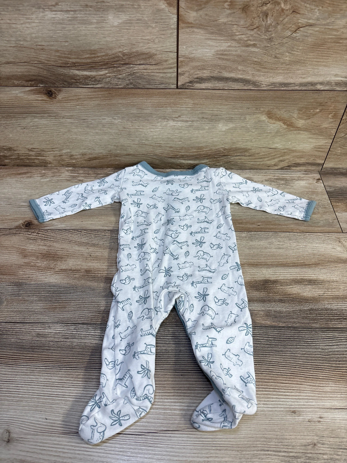 Back view of white footed baby sleeper showcasing all-over gray animal and leaf print with gray trim laid flat on wood background