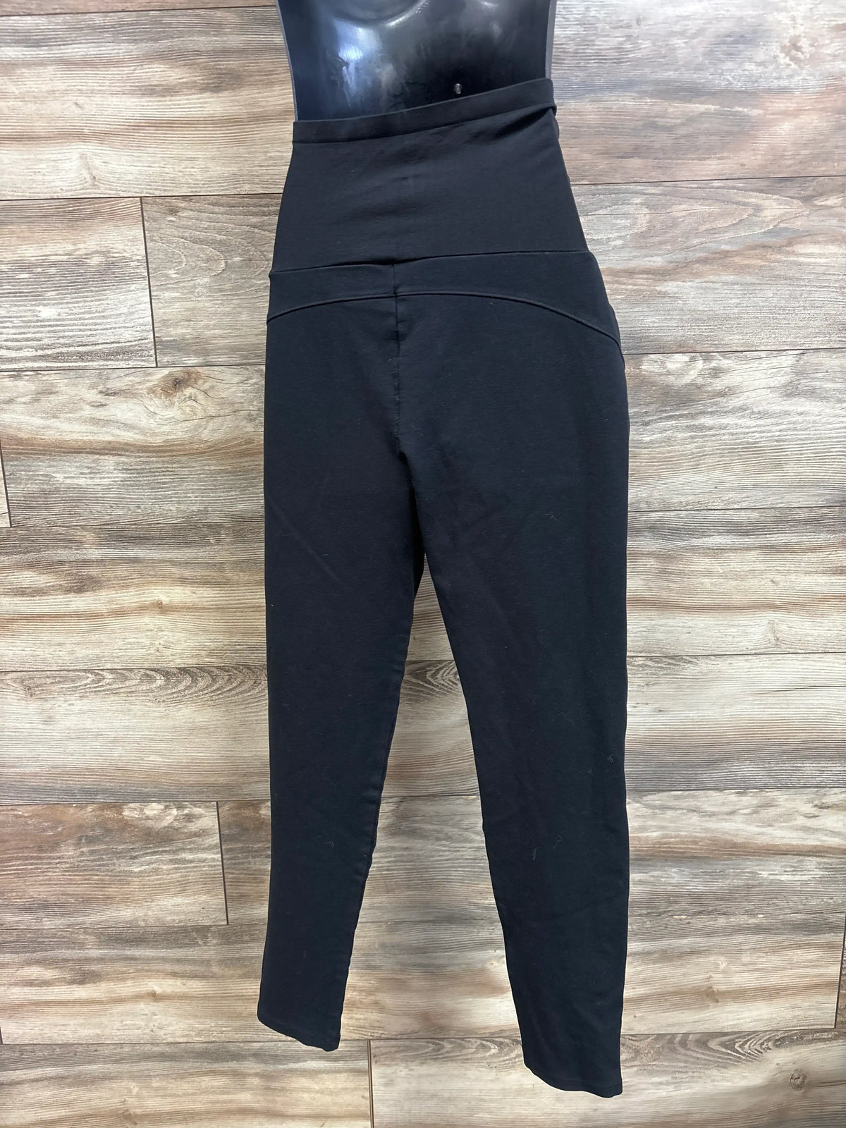 Front view of Time and Tru black maternity full panel pants showcasing the over belly panel on a wood look floor