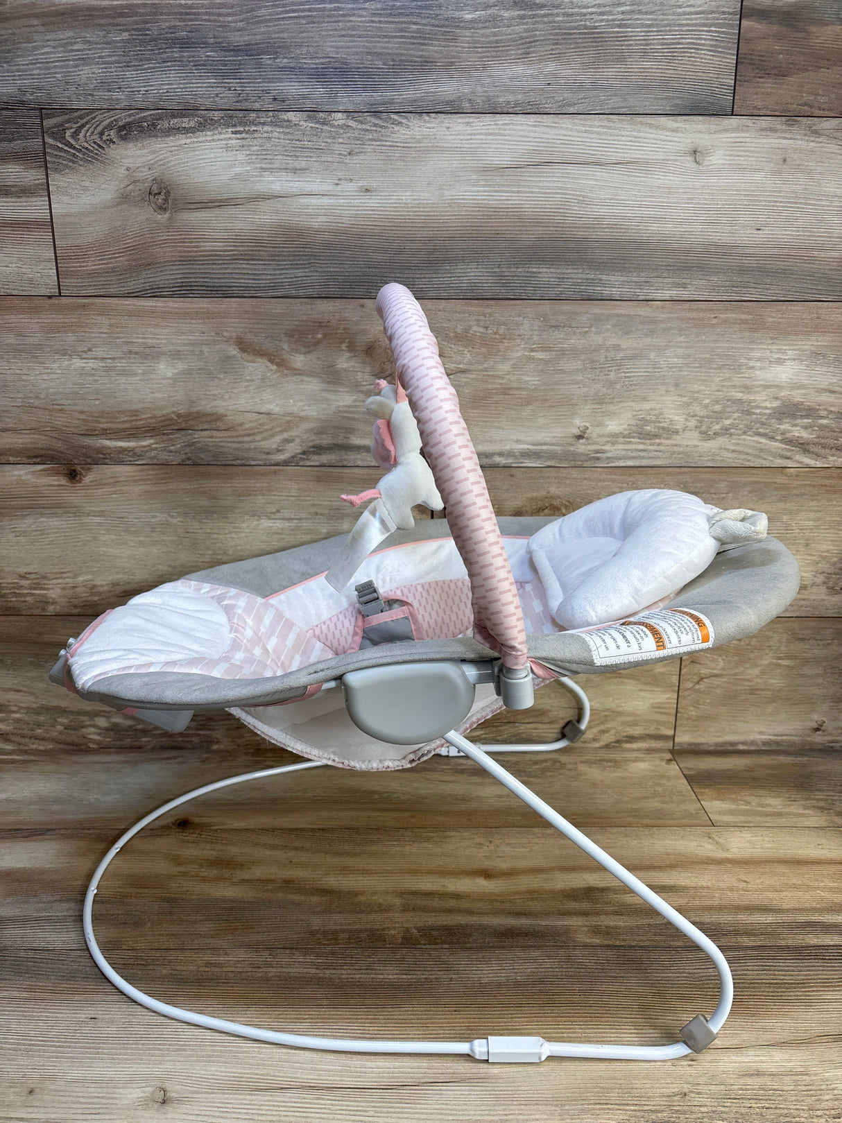 Pink and gray baby bouncer with plush toy, ideal for infant comfort and play