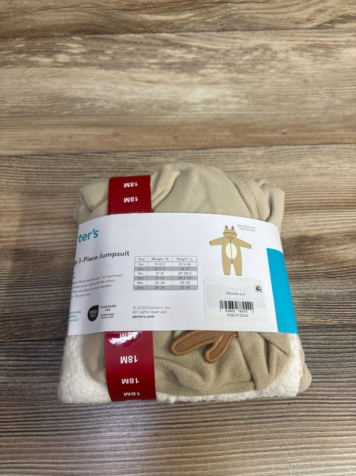 Folded Carter's beige and white baby jumpsuit size 18M with bear detail on wood background