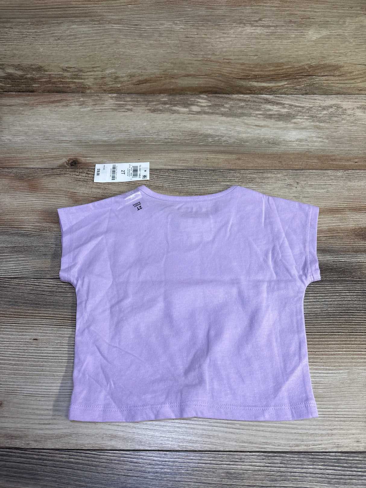 Back view of Epic Threads toddler lilac t-shirt showcasing short sleeves and visible size 2T tag on wood background
