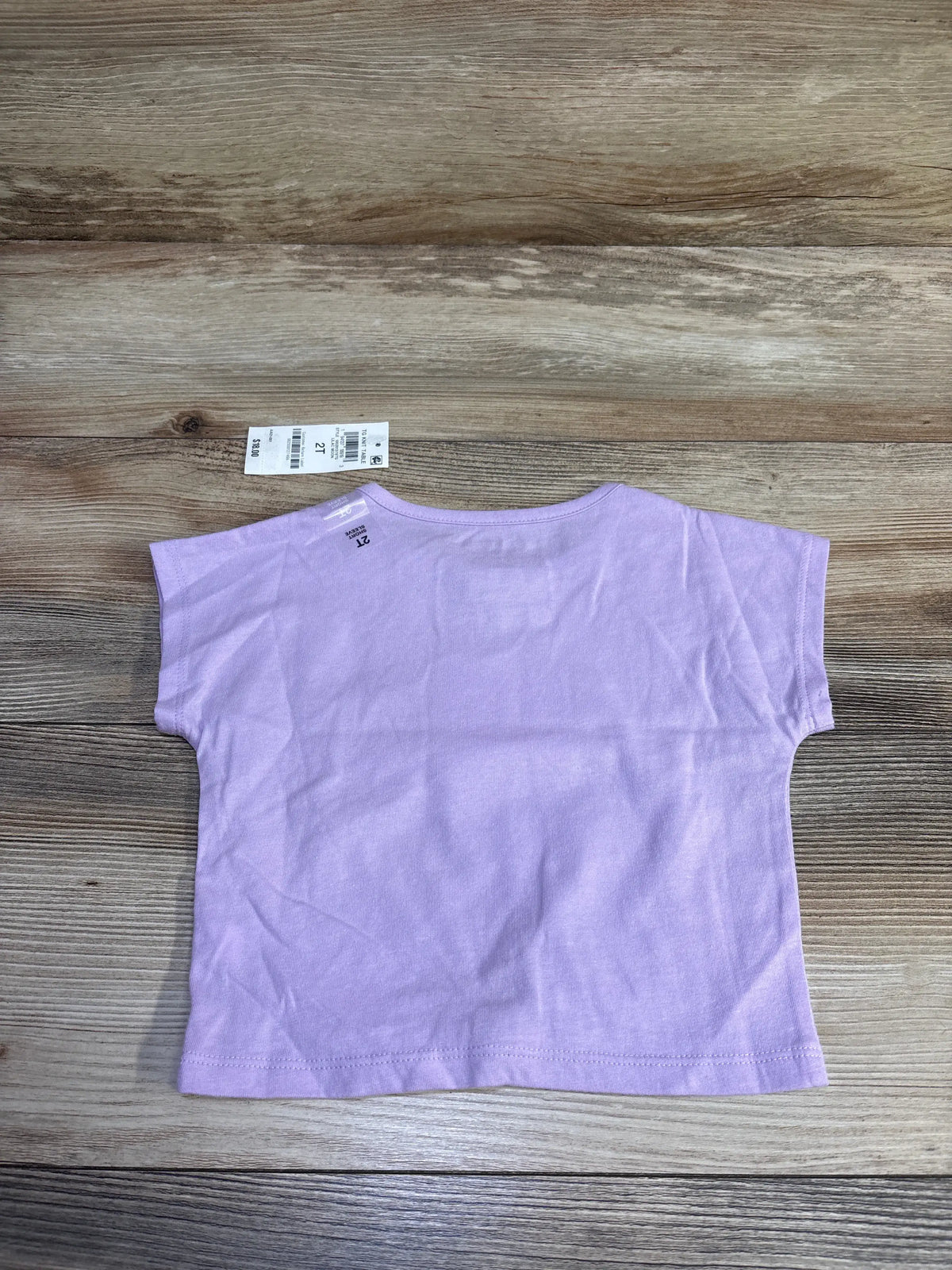 Back view of Epic Threads toddler lilac t-shirt showcasing short sleeves and visible size 2T tag on wood background