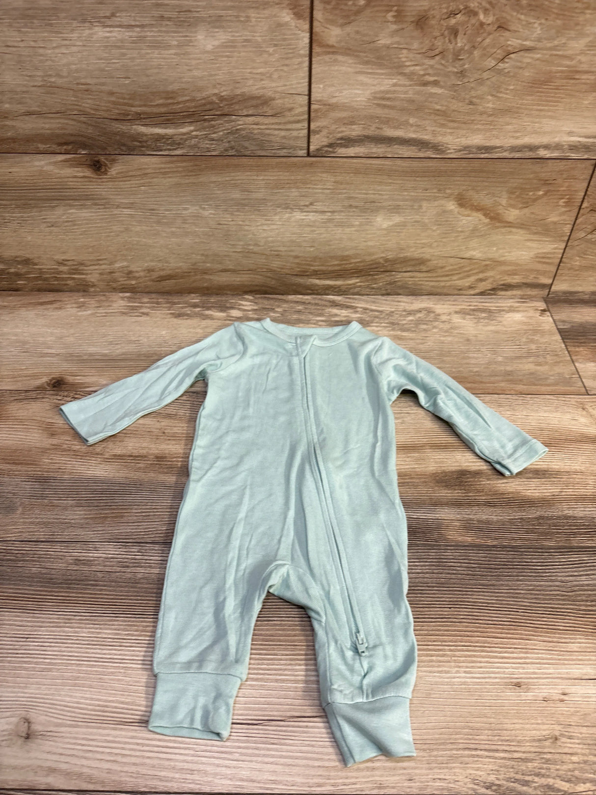 Front view of Cloud Island modal baby sleeper in sage green with long sleeves, zip front, and fold-over cuffs on wood background