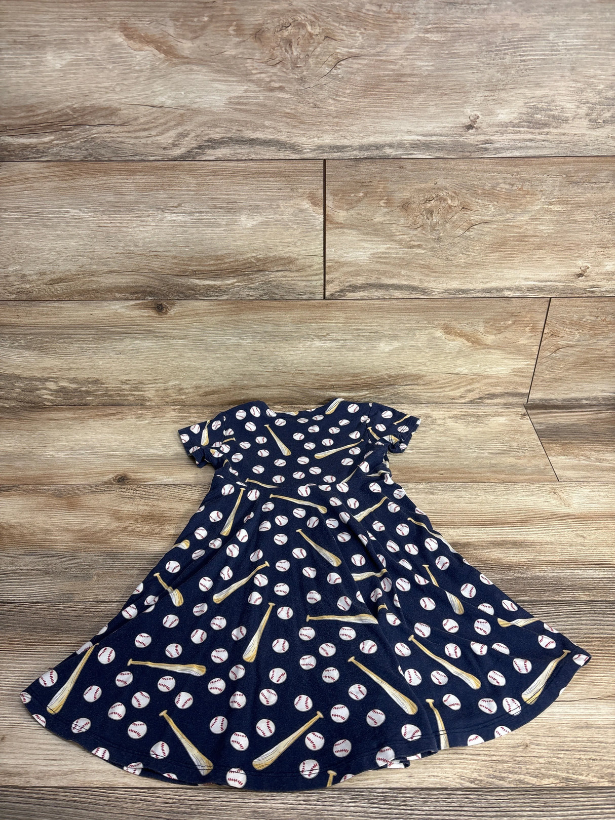 Navy blue toddler dress with baseball and bat print on wooden floor background