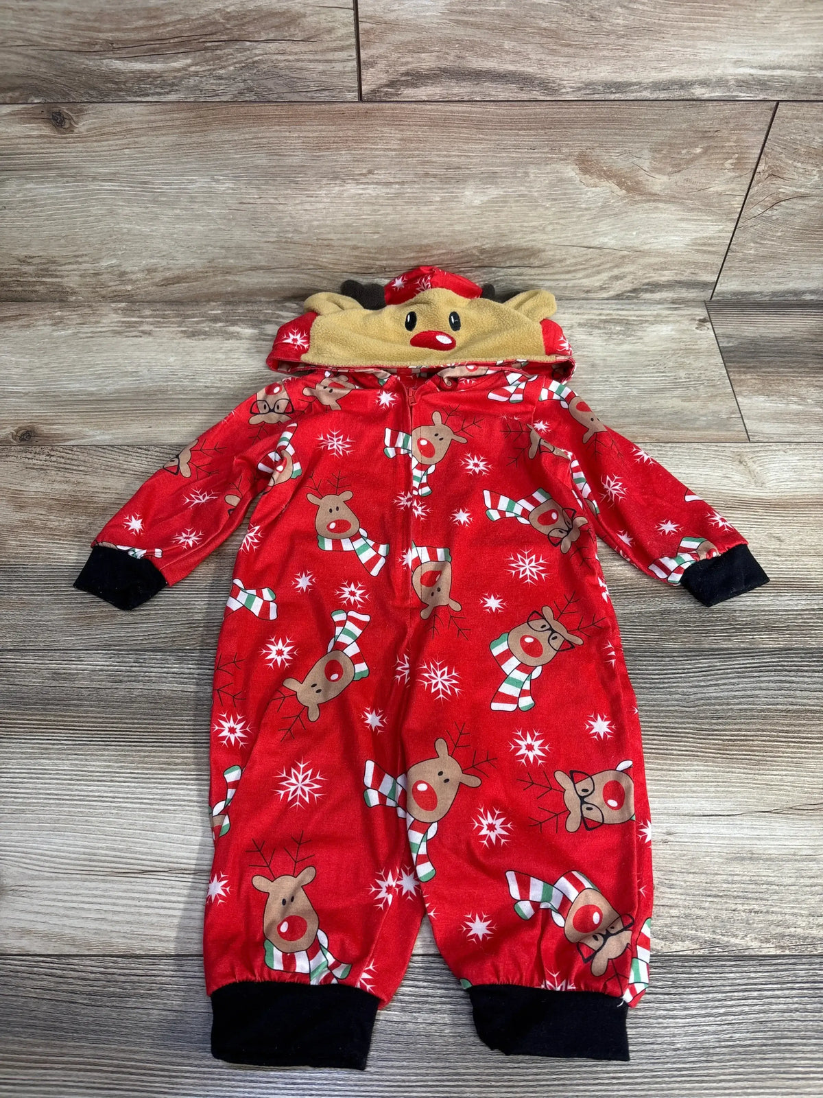 Red reindeer print baby onesie with hood, snowflakes, candy canes, and black cuffs on wood floor