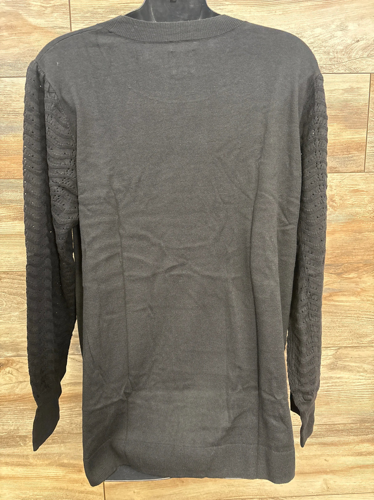Front view of black Gap maternity CashSoft pointelle sweater with pointelle-knit sleeves and ribbed hem on wood paneling