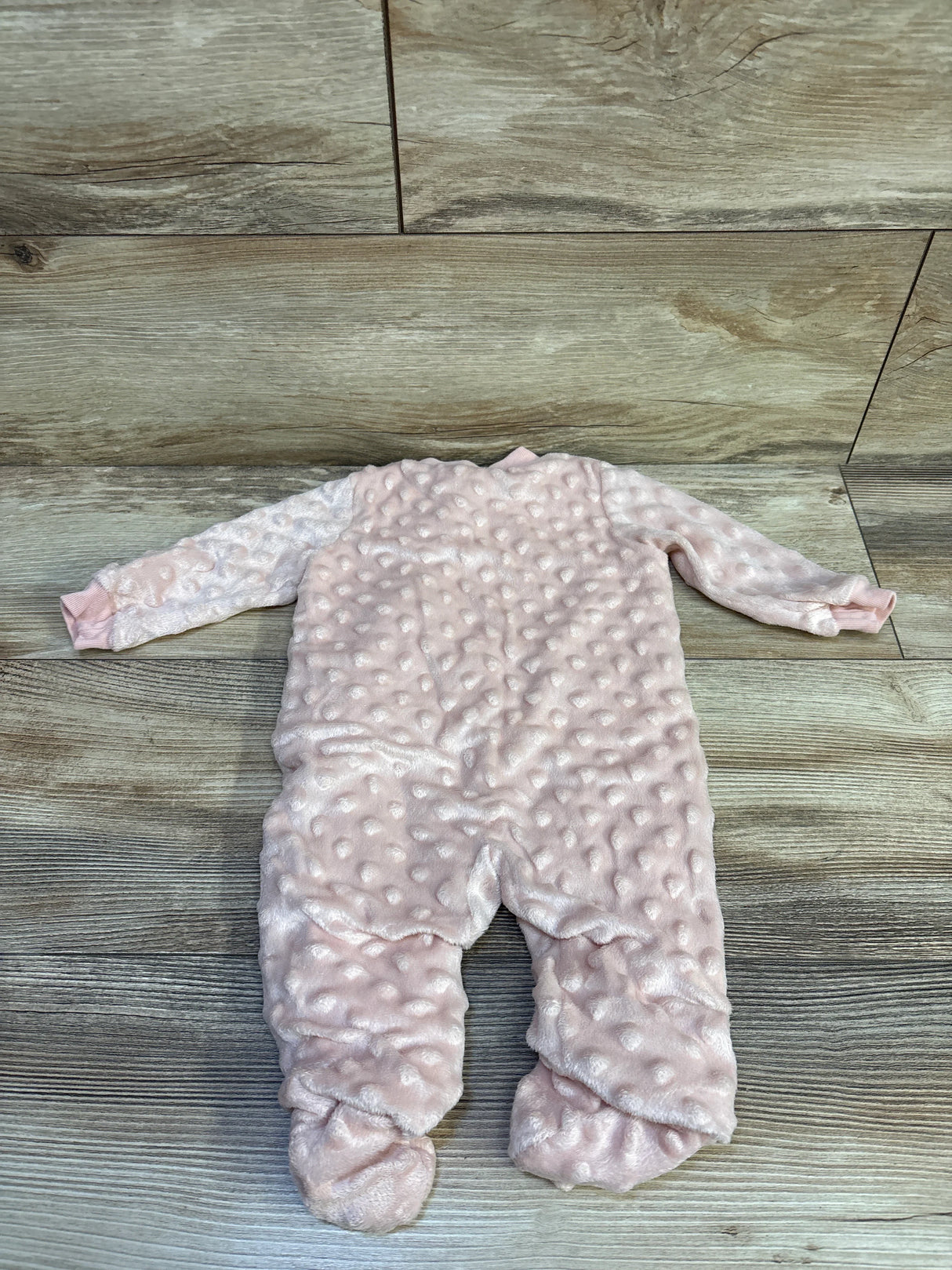 Back view of Kyle & Deena Minky Dot footed sleeper showcasing pink raised dot minky texture and ribbed cuffs on wood floor background