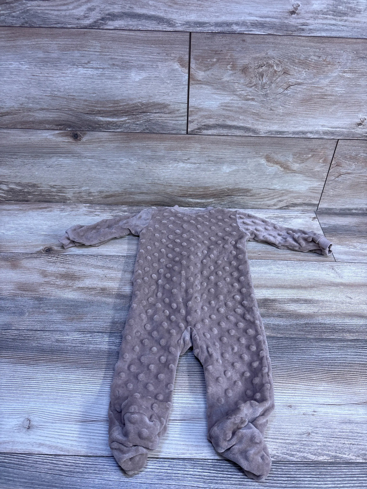 Flat lay of DreamGro Minky Dot footie sleeper 3-6m showing textured dot fabric and enclosed feet on light wood floor