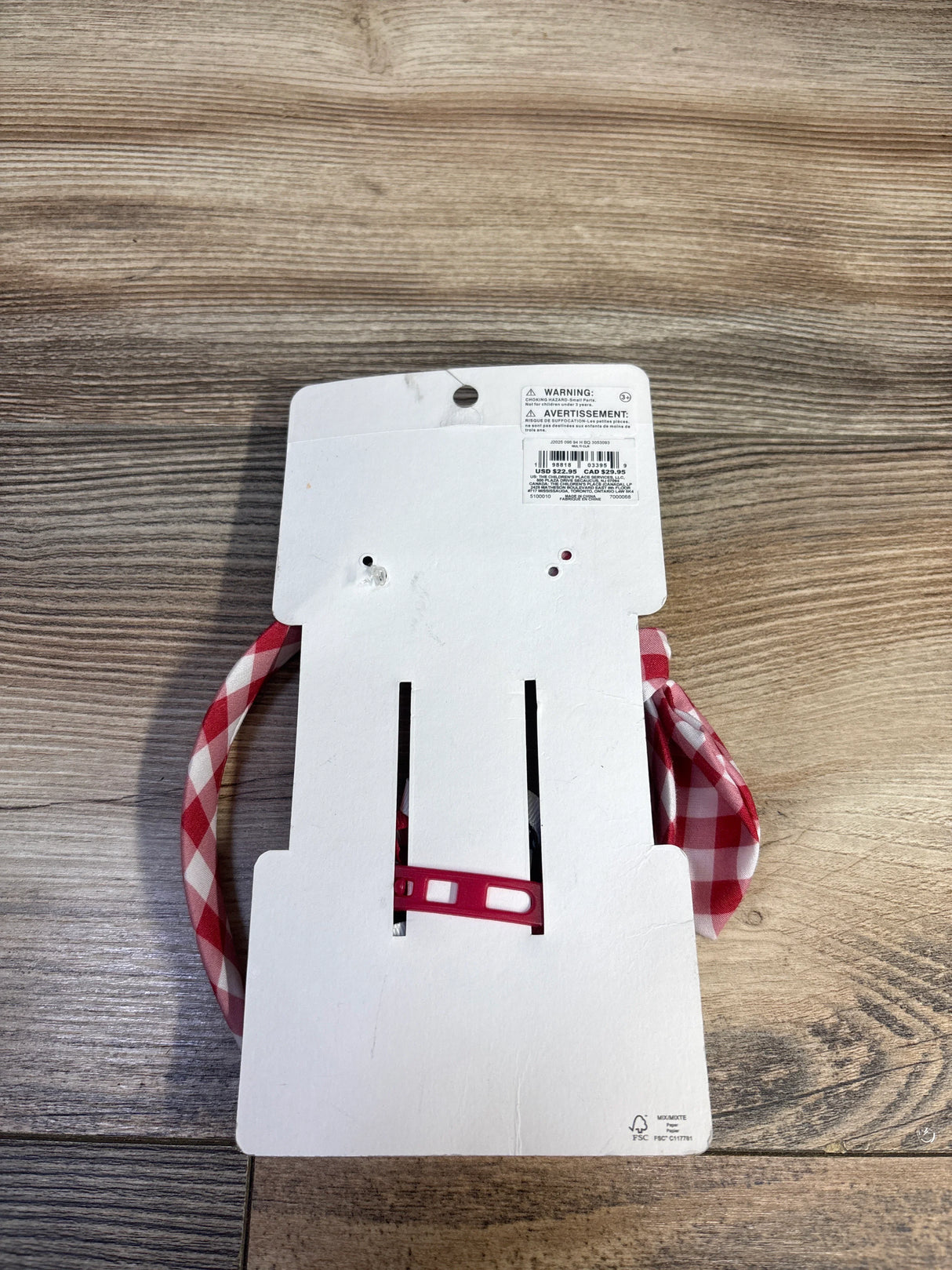Top view of Gymboree headband and bow set with red-and-white gingham pattern on white cardboard backing