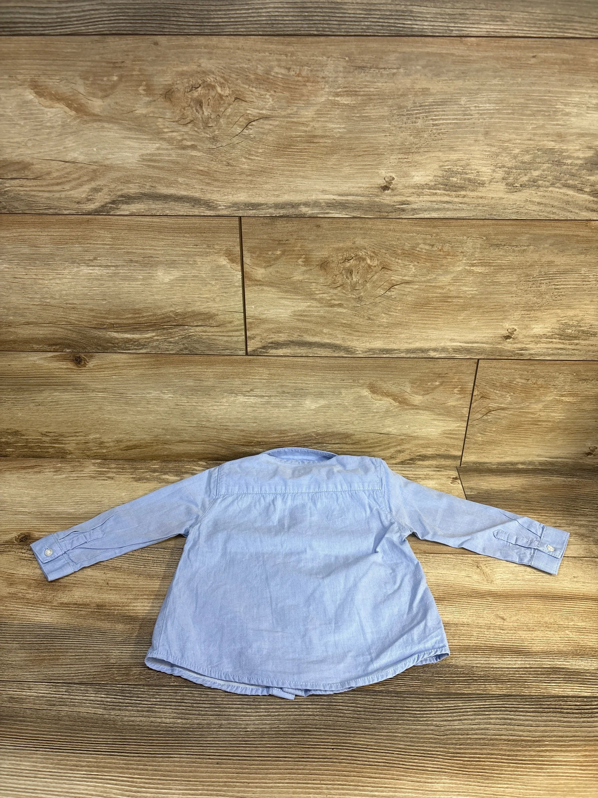 Light blue kids long sleeve button-up shirt on wood floor, kids clothing resale