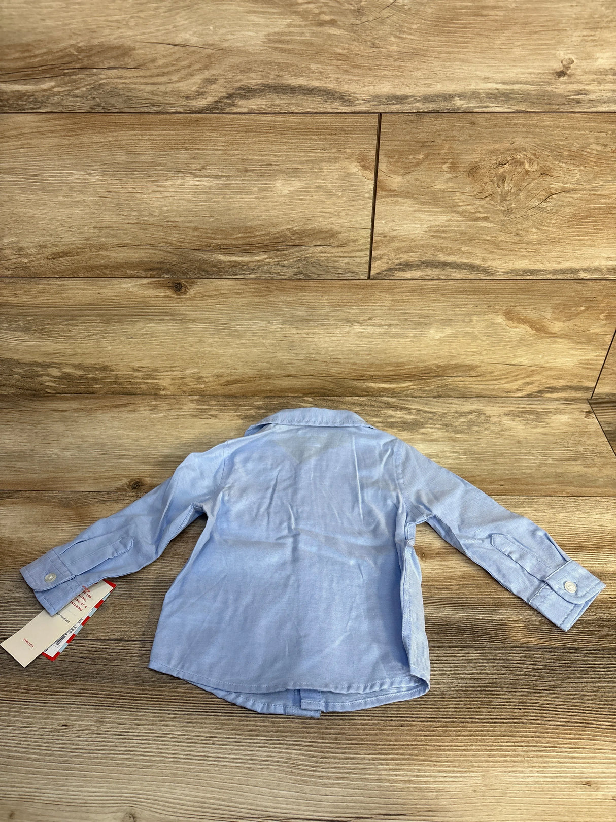 Light blue long sleeve toddler shirt on wood background with tags attached