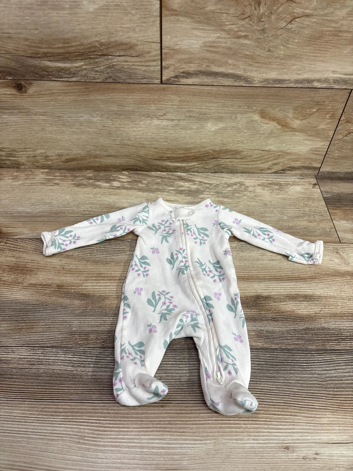 Carter's ribbed ivory preemie sleeper with purple floral print on a wooden background