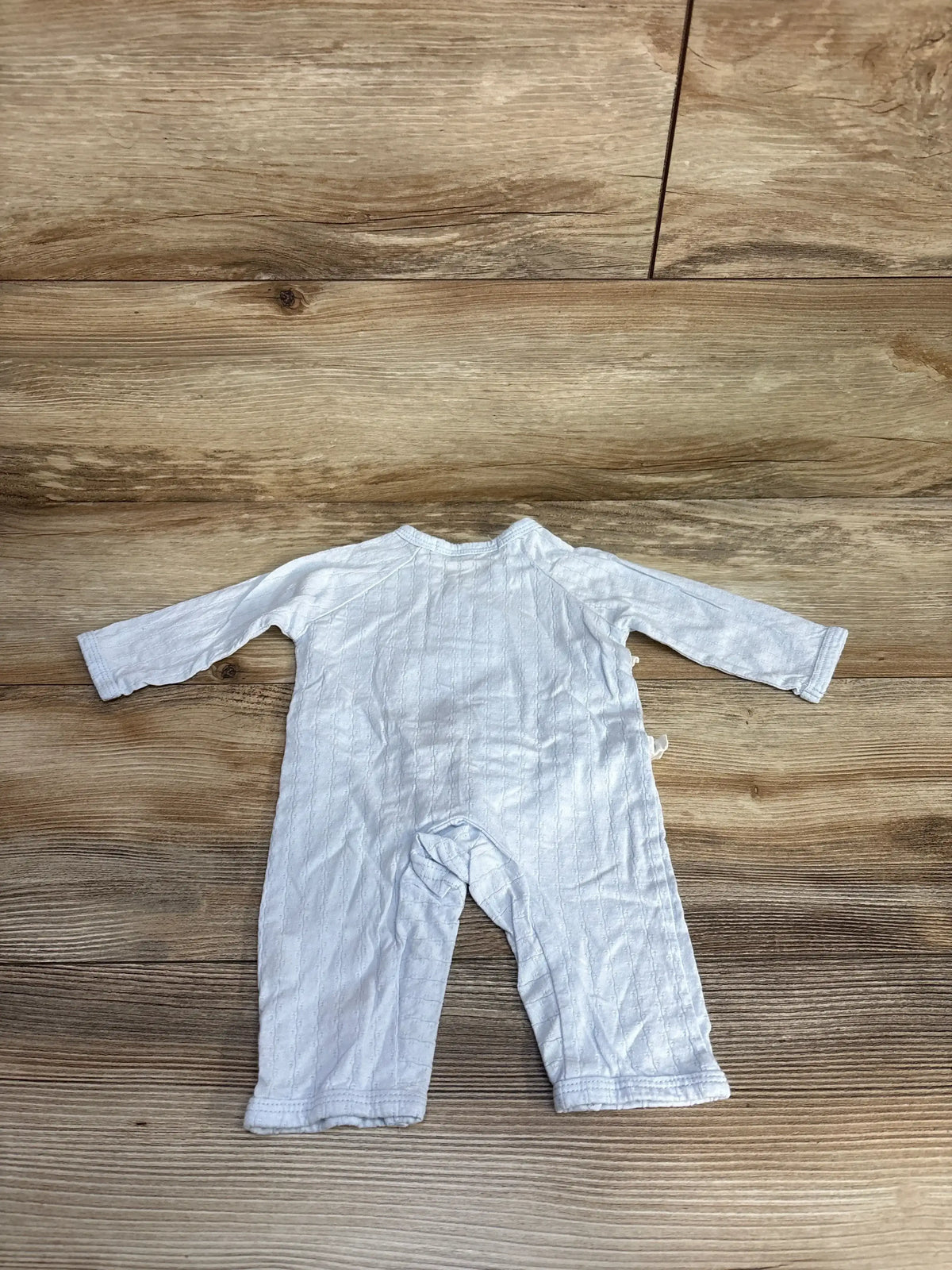Flat lay of Shein kimono coverall in light blue, showing long sleeves and front snap closures on wooden background