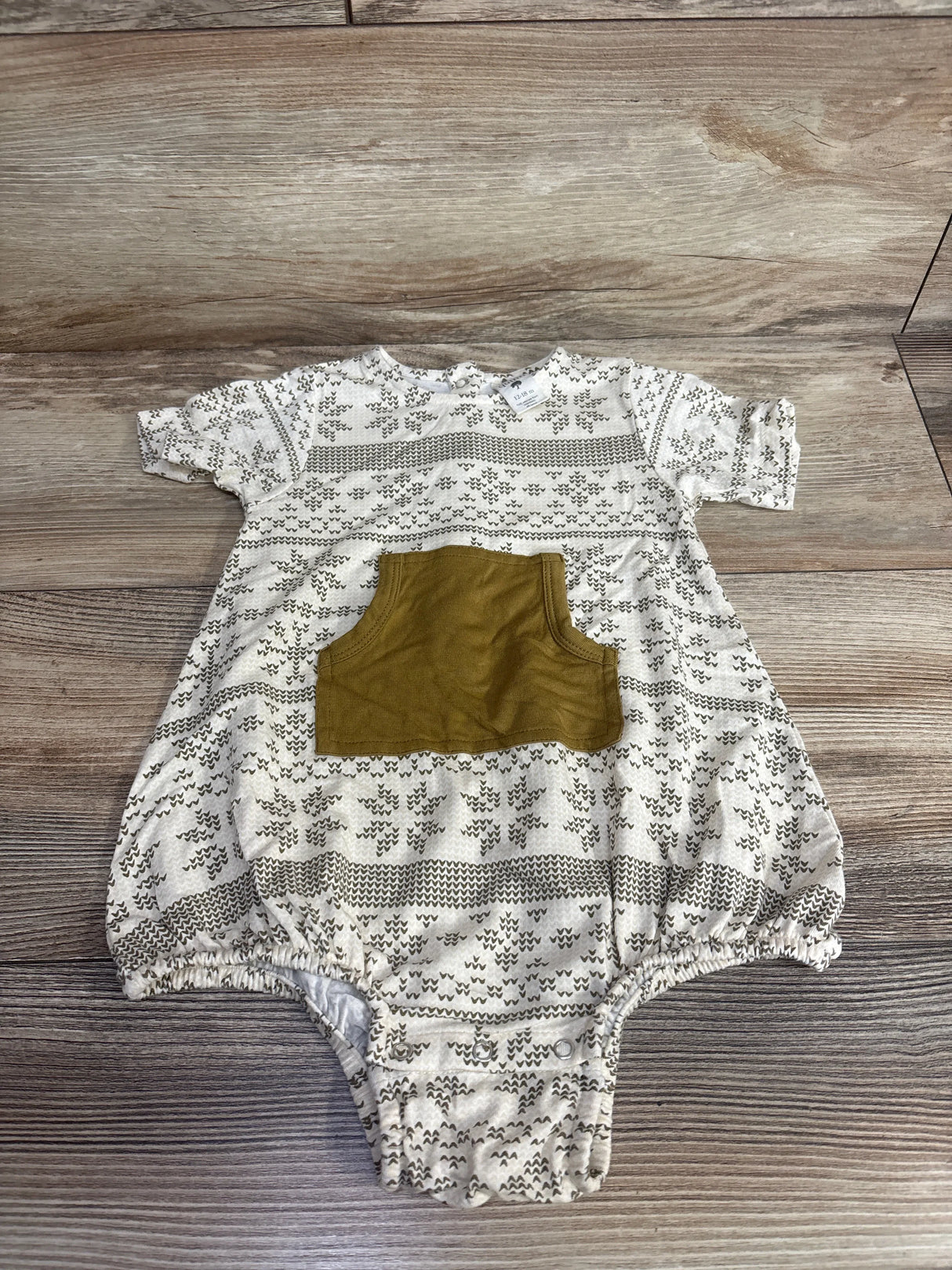 Patterned short sleeve baby romper with brown front pocket on wood background
