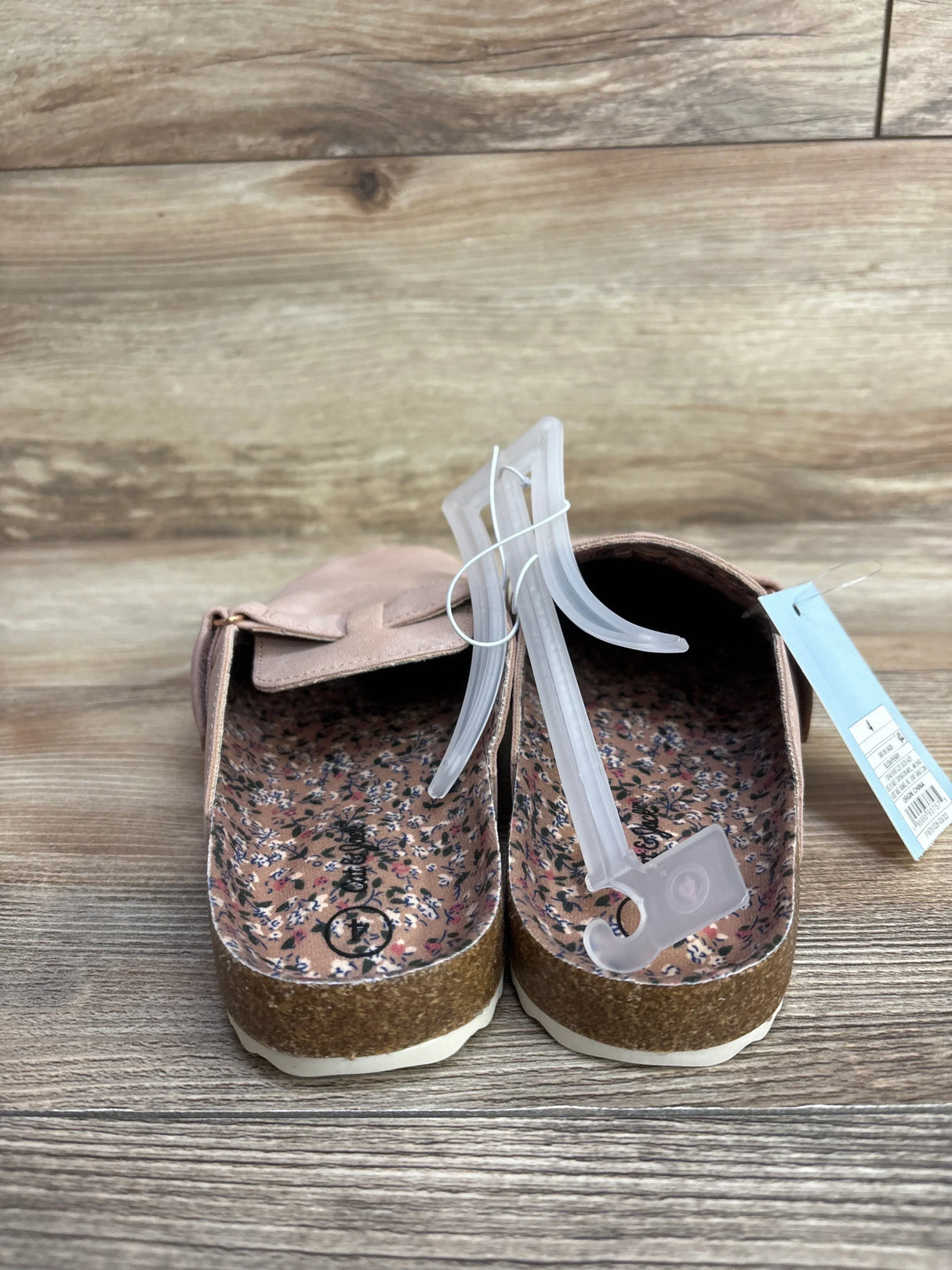 Pink children's slip-on shoes with floral insoles and cork soles on wood background